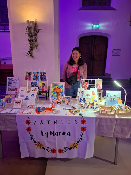 Colourful market stall with handmade mugs, cards, tote bags, and stickers by a local artist at Swan Market Utrecht.