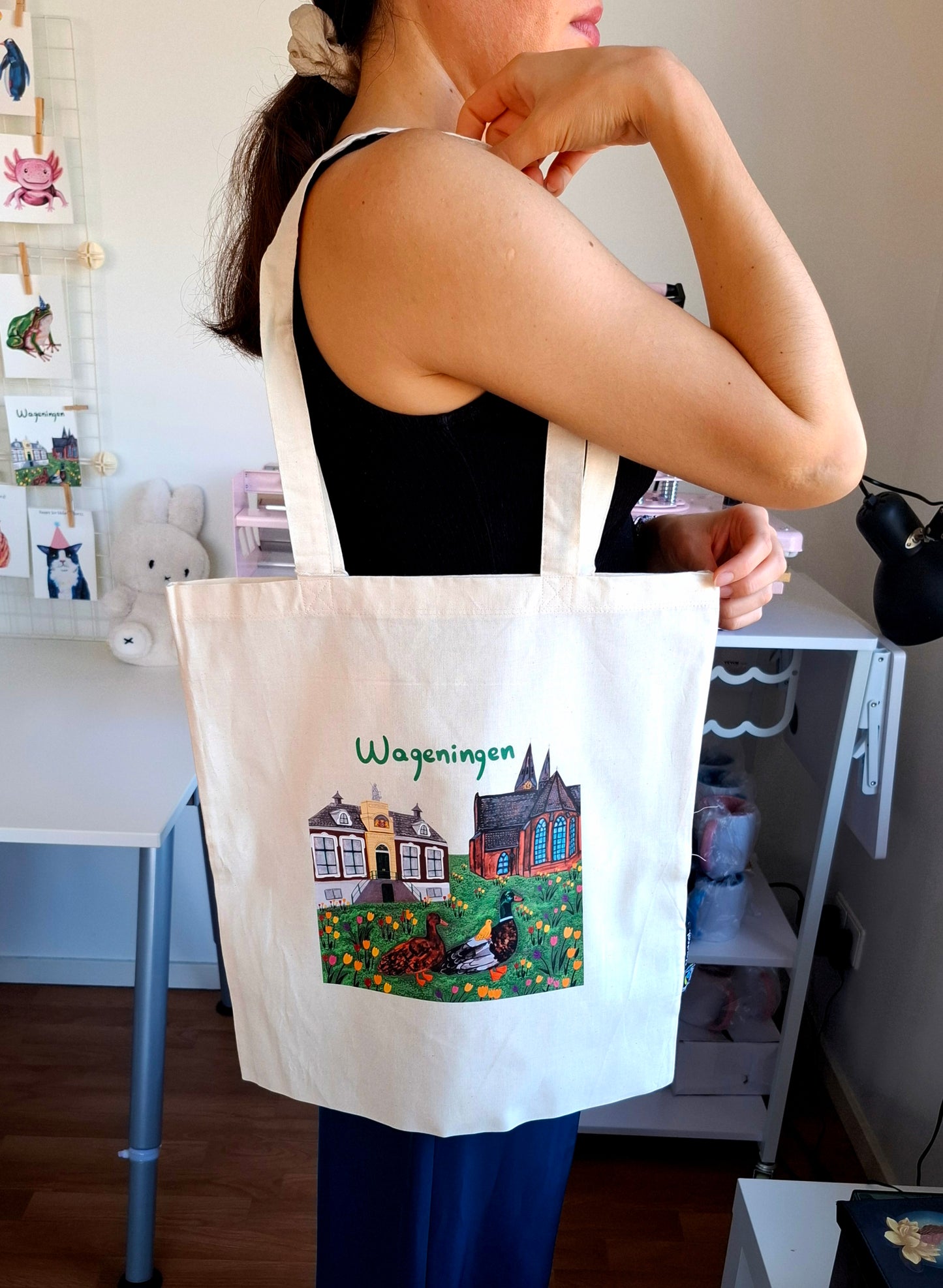 Person holding a tote bag with a printed Wageningen design.