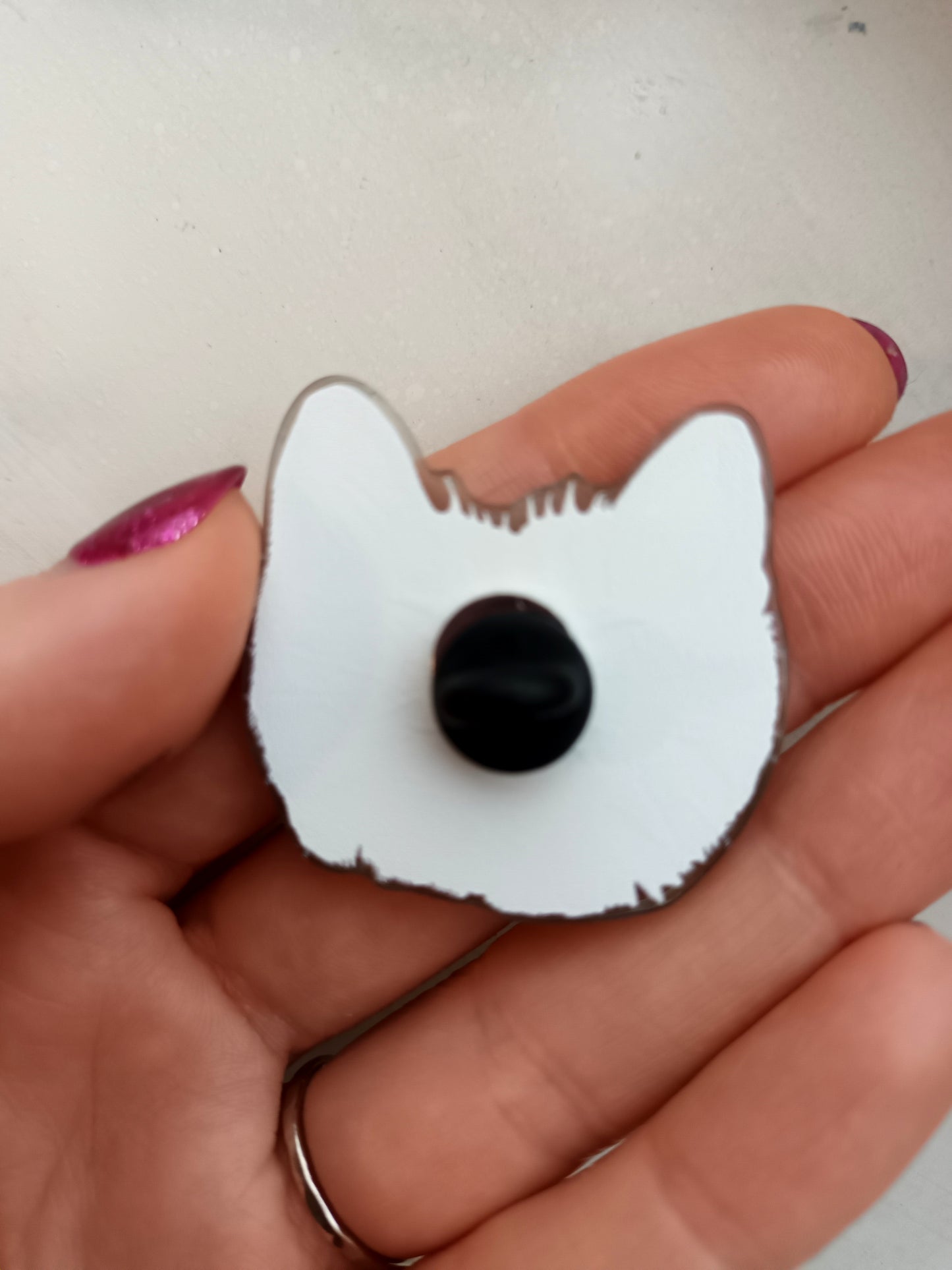 Cute orange cat face acrylic pin with a soft PVC clutch. High-quality glossy finish, perfect for jackets, bags, or collectors, back of the pin.