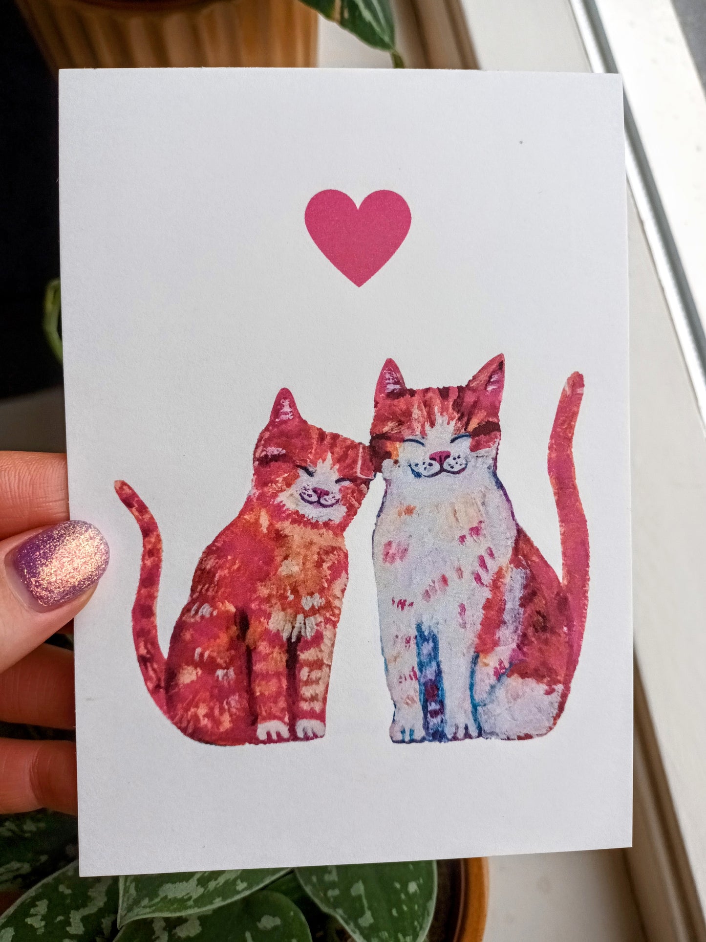 Handmade postcard featuring a full-body illustration of two loving cats sitting together, tails intertwined, high-quality romantic art card held by hand