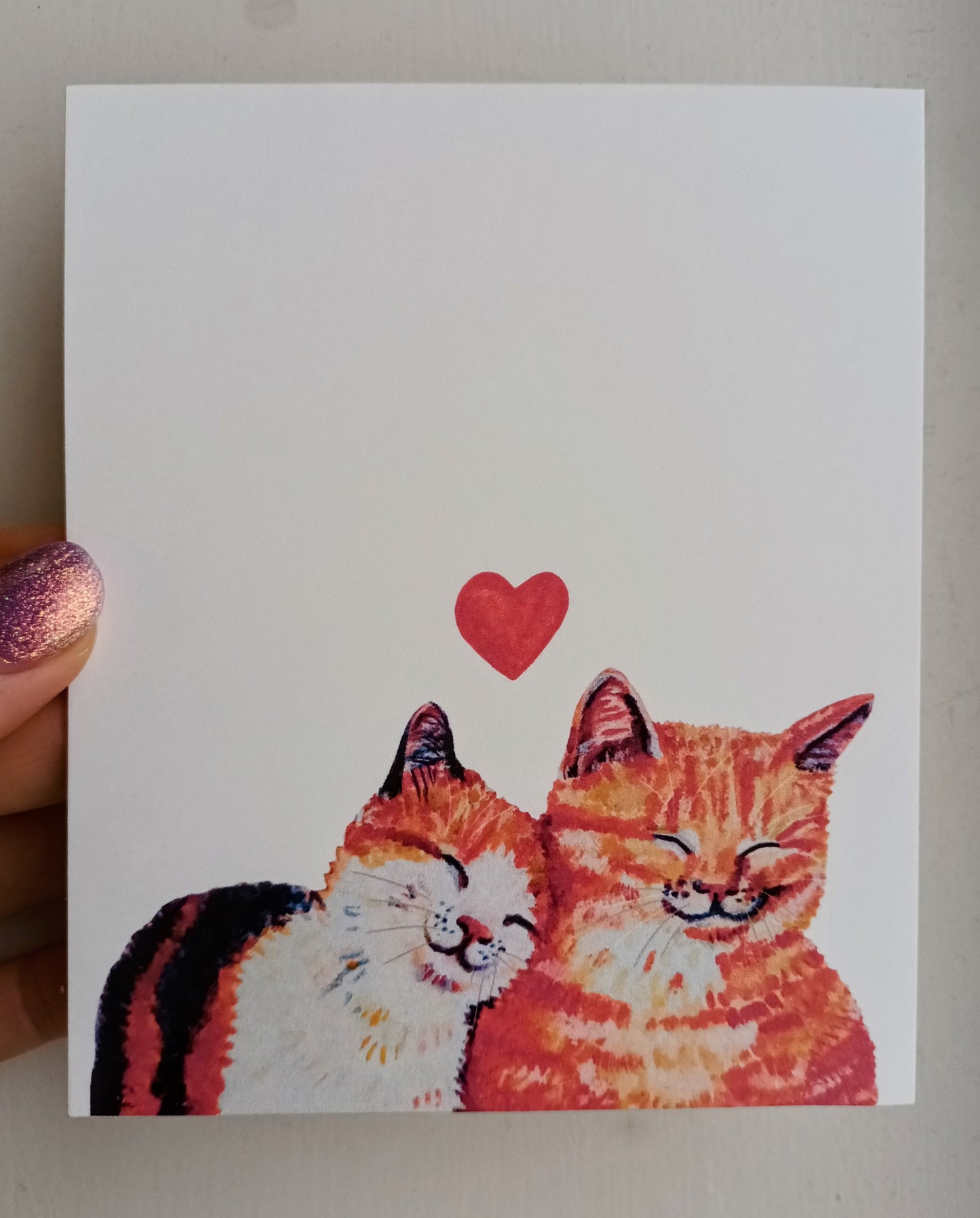 Handmade postcard featuring a close-up illustration of two cute cats in love, snuggling together, high-quality art card held by hand