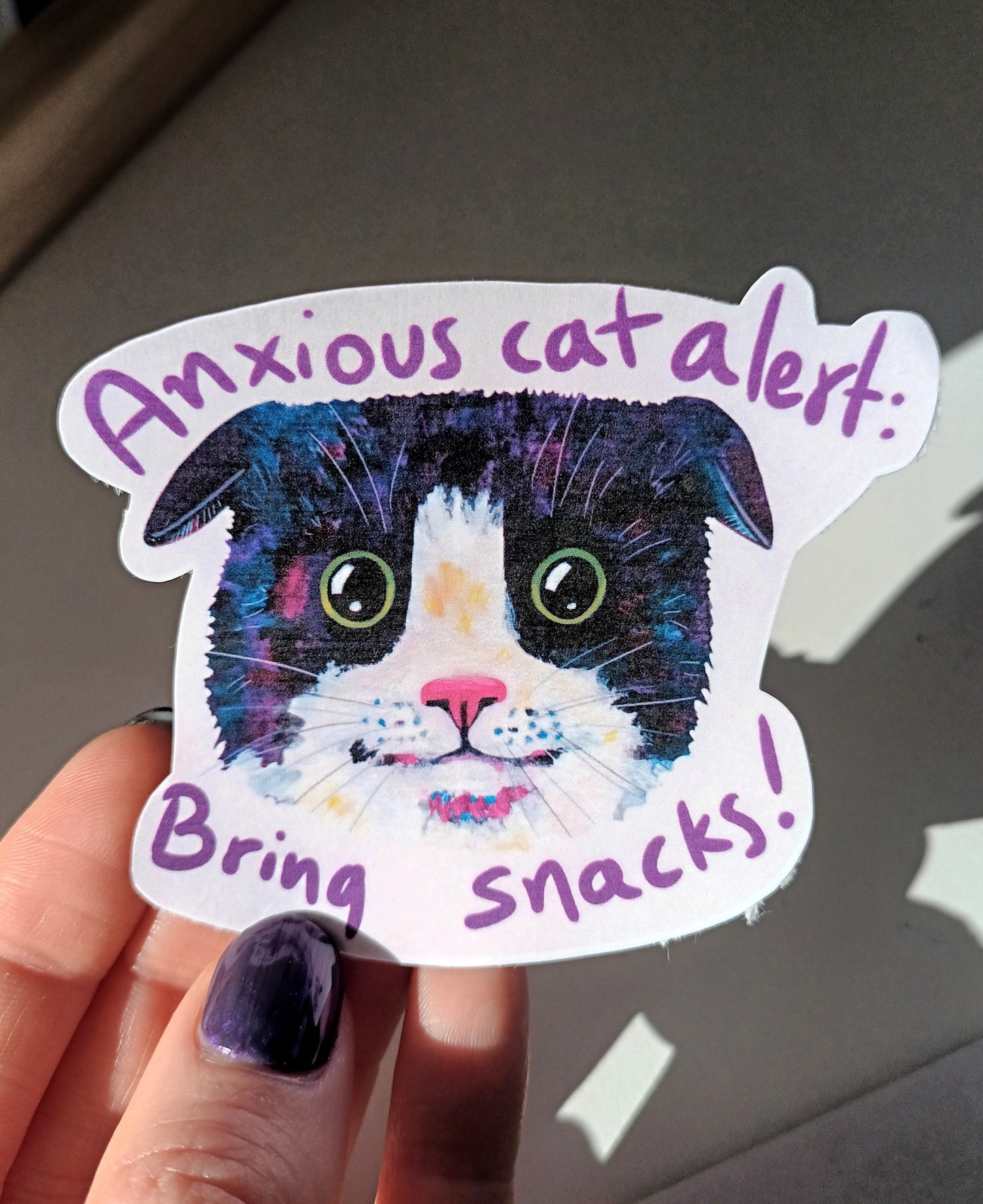 Cute anxious cat sticker with the text 'Bring Snacks', hand-drawn on waterproof vinyl, perfect for decorating laptops and water bottles, held by hand.