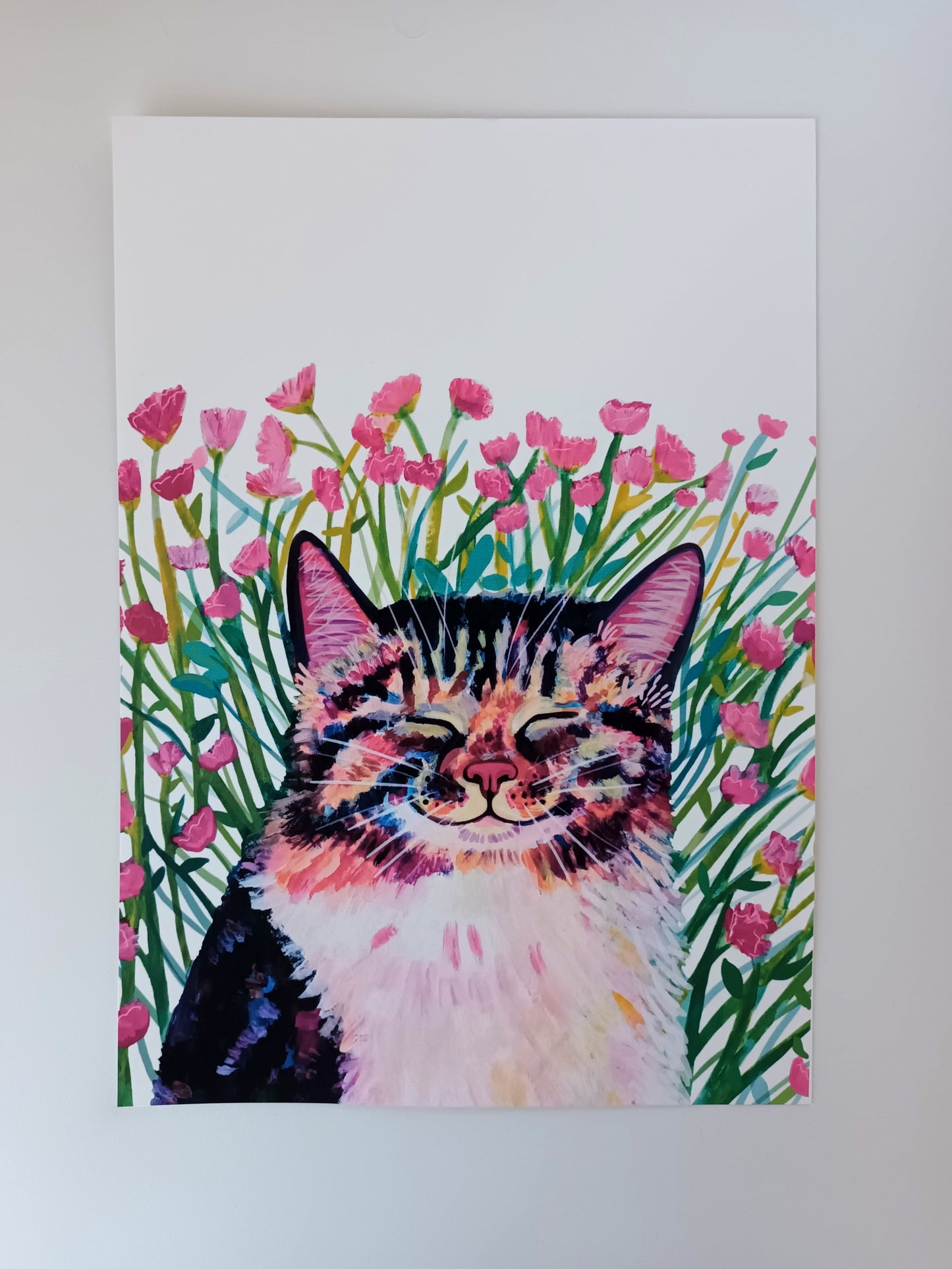 A4 art print of a cute cat sitting in a meadow of pink flowers on a table, printed on eco-friendly matte paper.