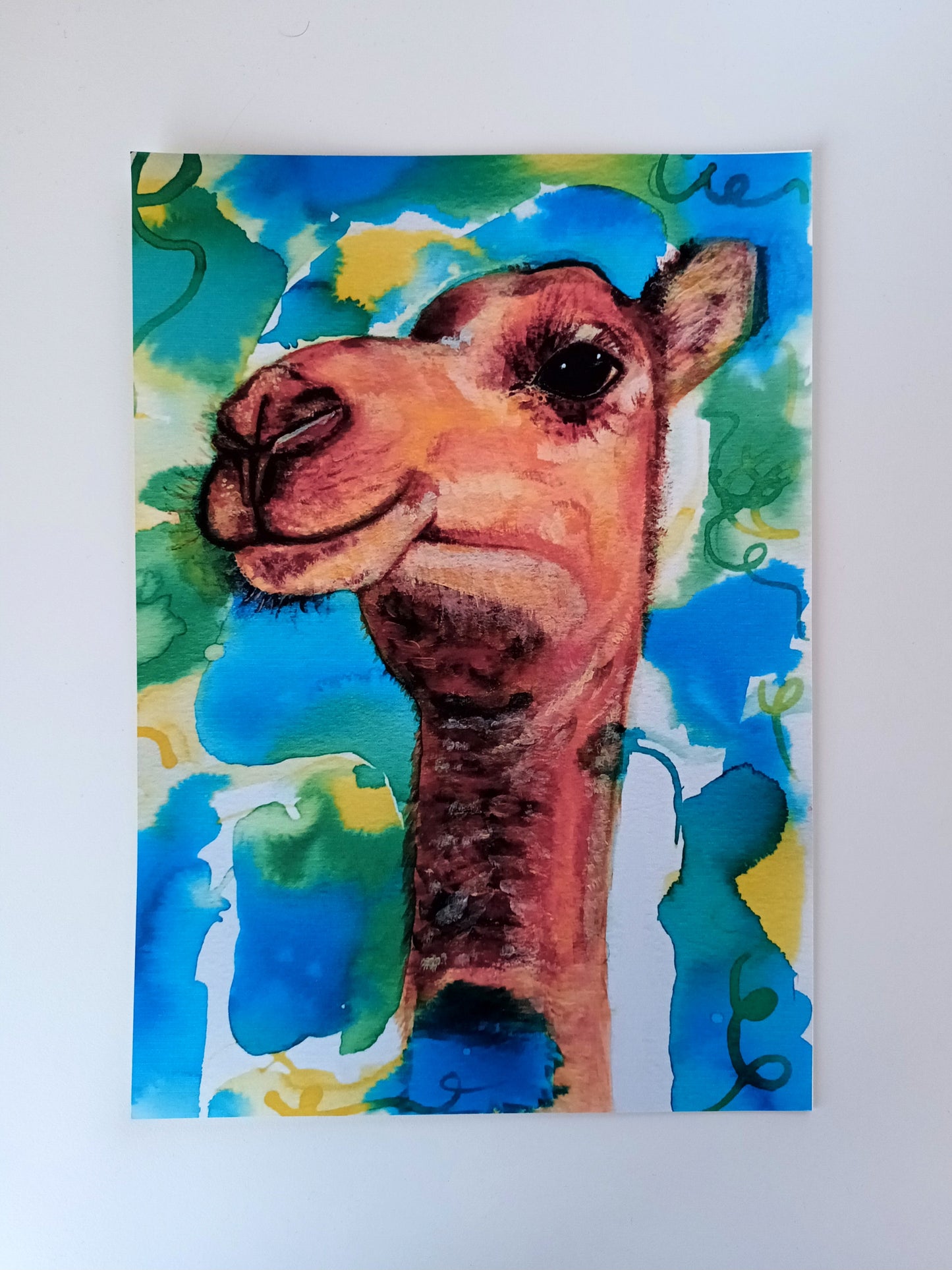 A4 art print of a funny camel with a vibrant colourful ink background on a table, printed on eco-friendly matte paper.