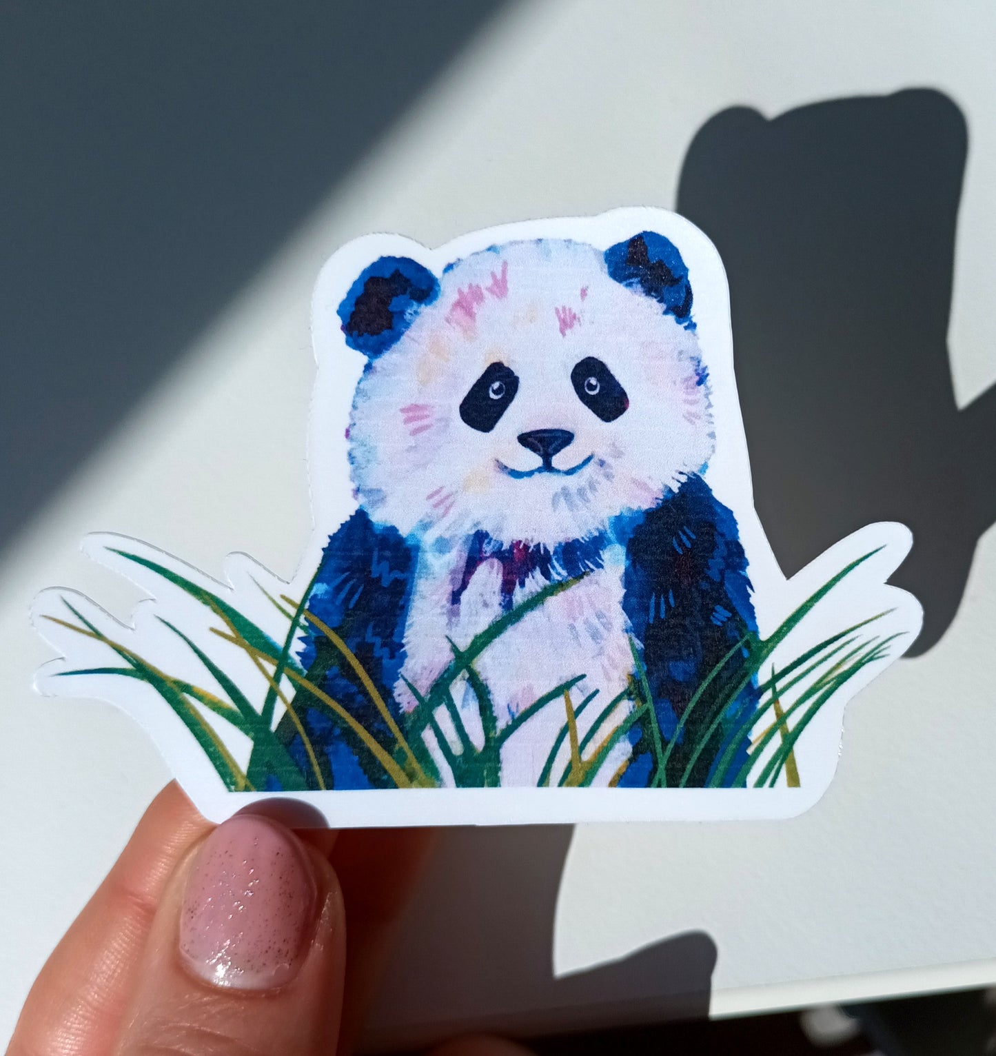 Cute waterproof sticker of a panda surrounded by green leaves with a matte finish held by hand.