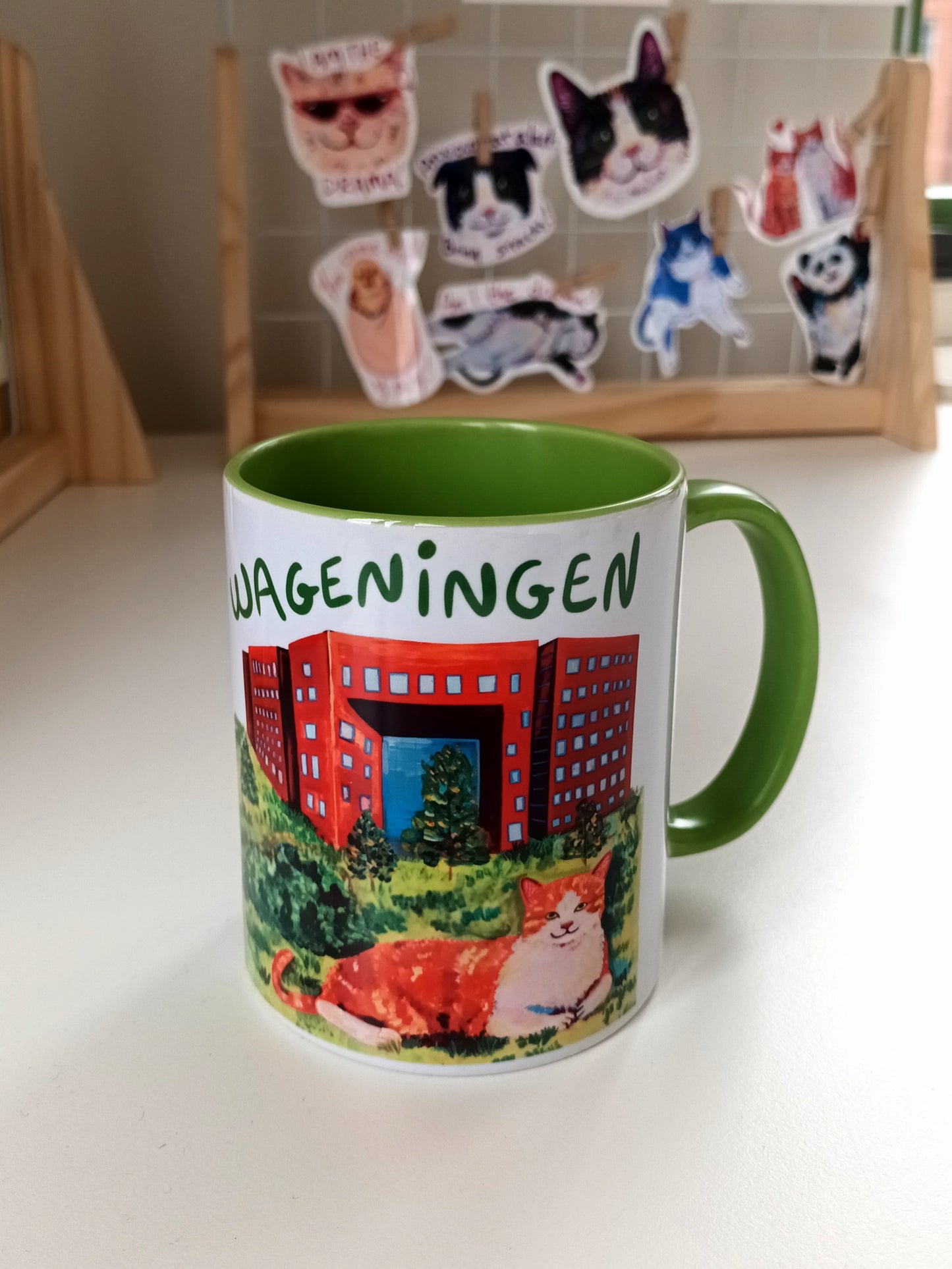 Handmade Wageningen mug with green handle and interior, featuring an orange cat sitting in the city.