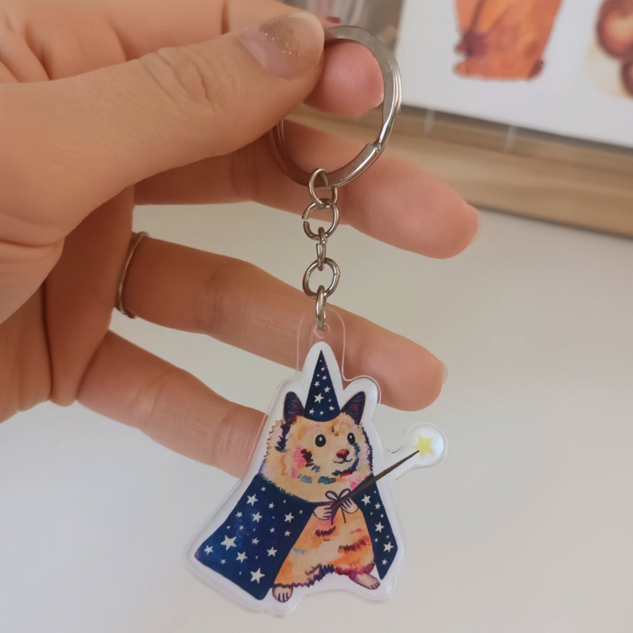 Handmade acrylic keychain of a cute hamster dressed as a magician with a wand and hat, stainless steel ring.
