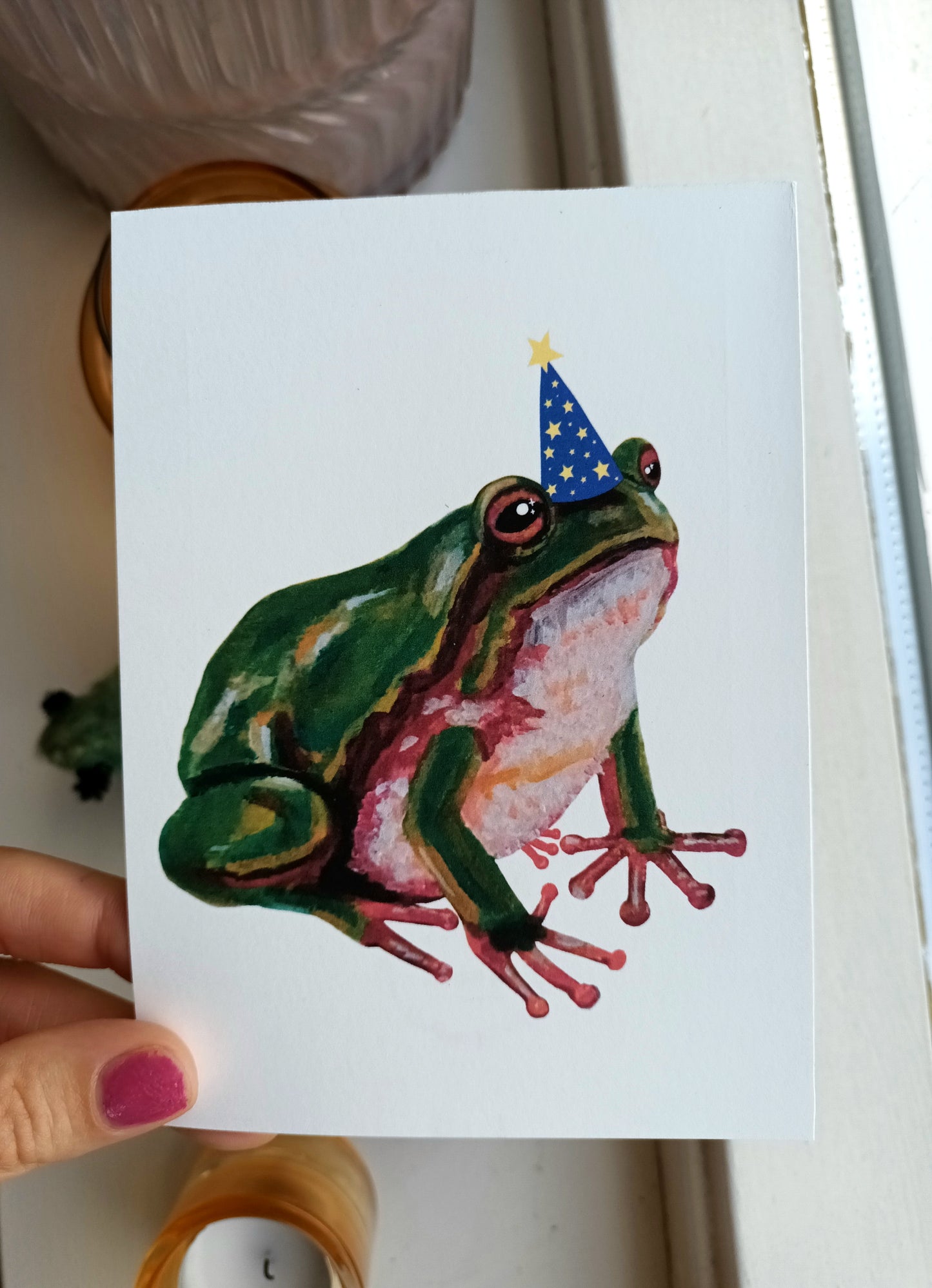 Postcard of a cute green frog wearing a wizard hat with sparkles around it, printed on A6 cardstock