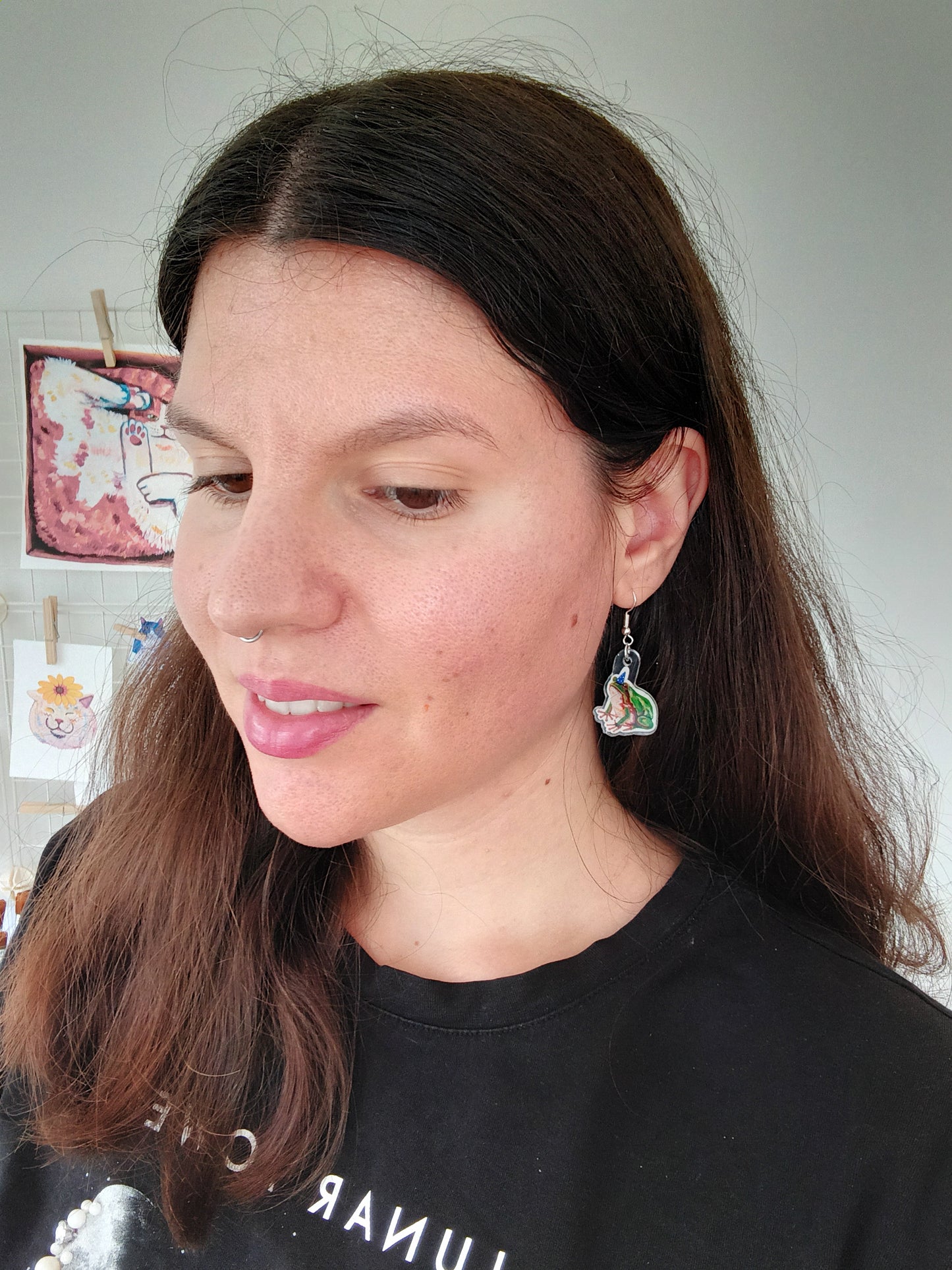 Woman wearing cute handmade frog earrings with a neutral background