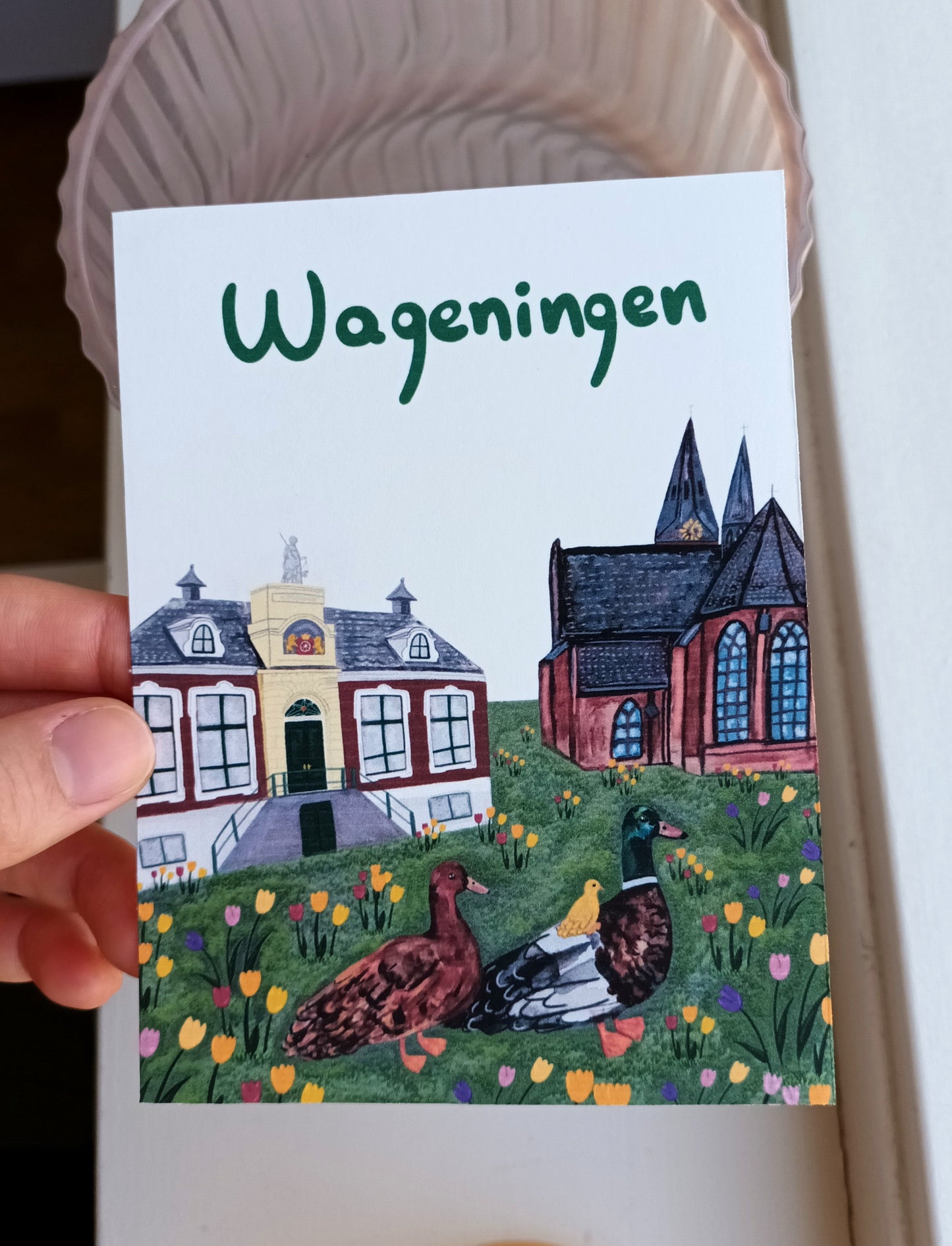 Card with illustration of buildings and ducks, featuring the word 'Wageningen'.
