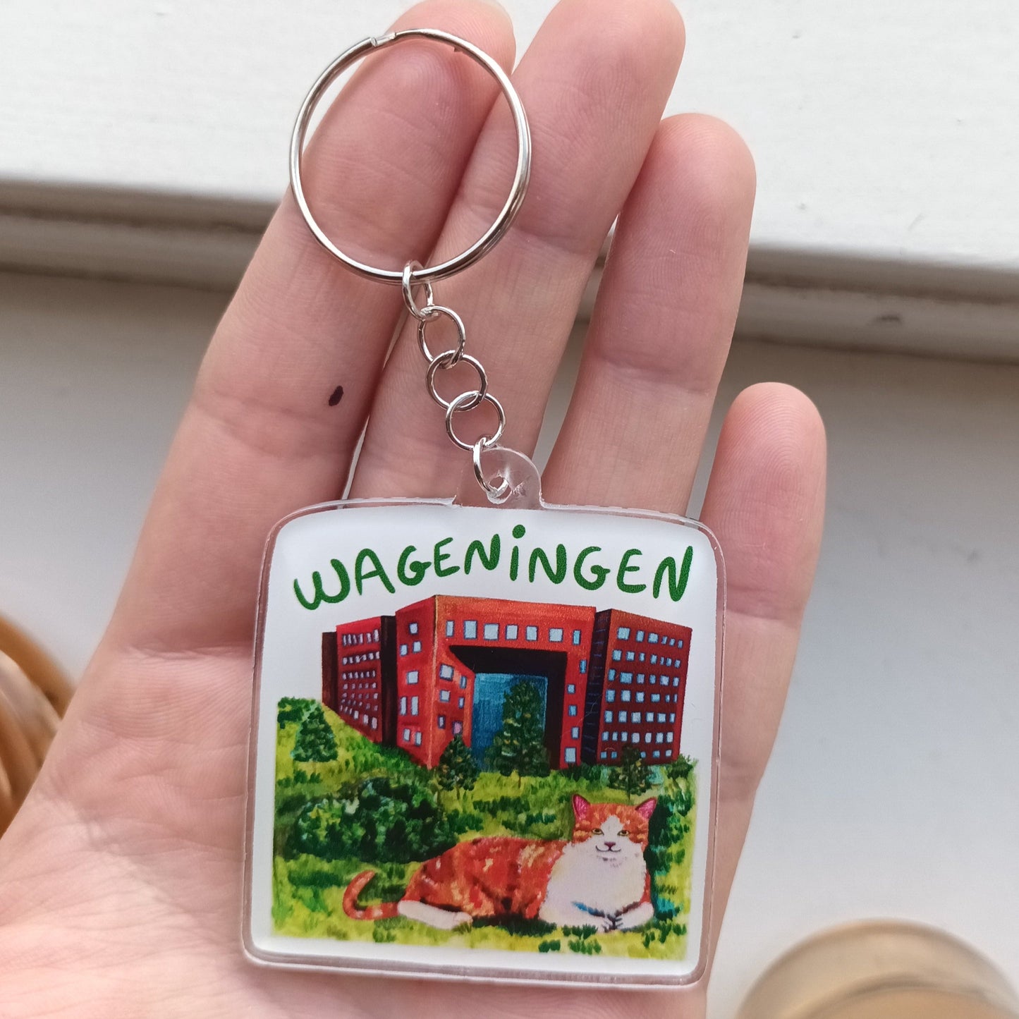 Acrylic Wageningen keychain with orange cat in front of Forum