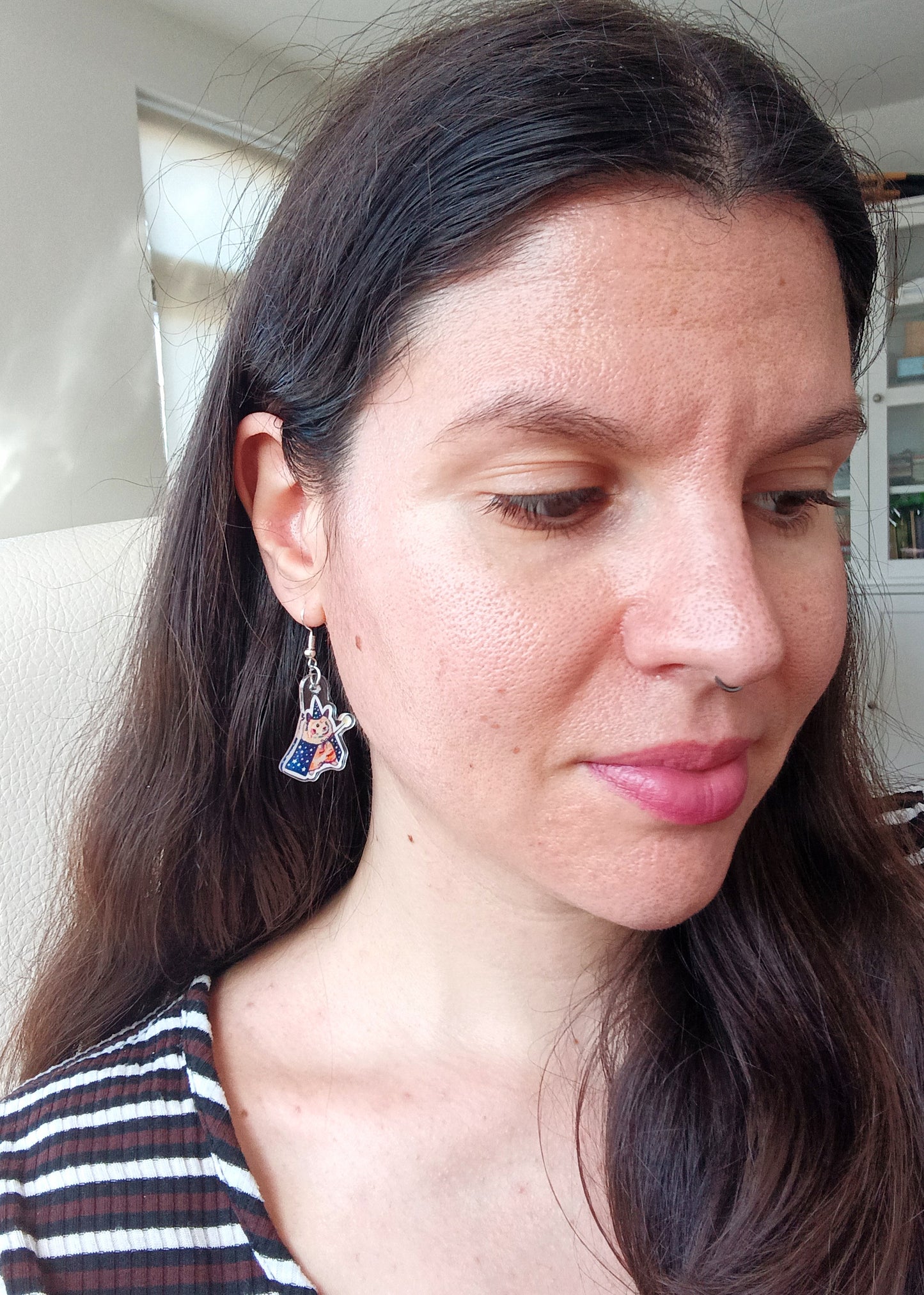 Woman wearing handmade hamster wizard earrings indoors
