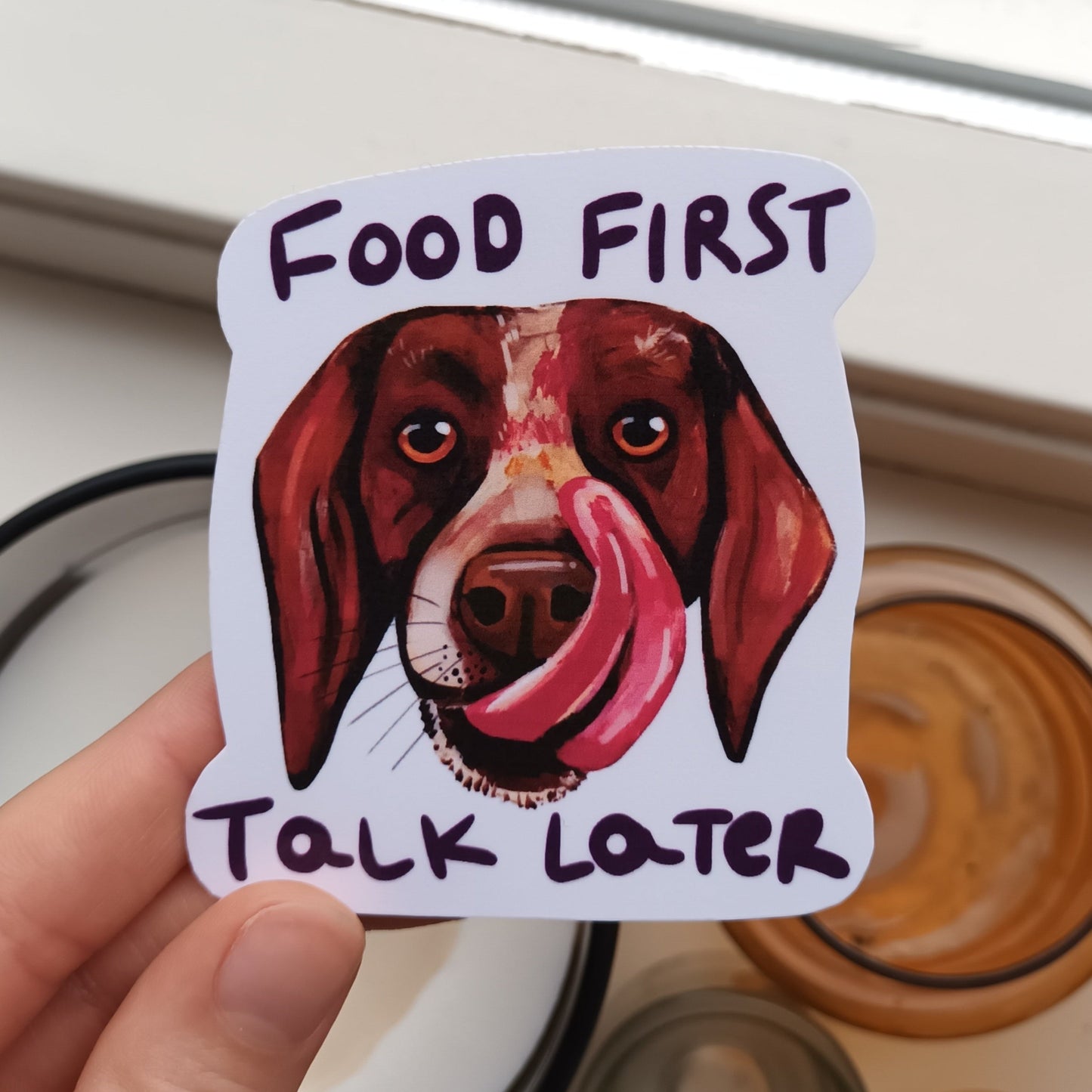 Dog Licking His Snout sticker with “Food First, Talk Later” text, original illustration by the artist, 7 x 7.87 cm