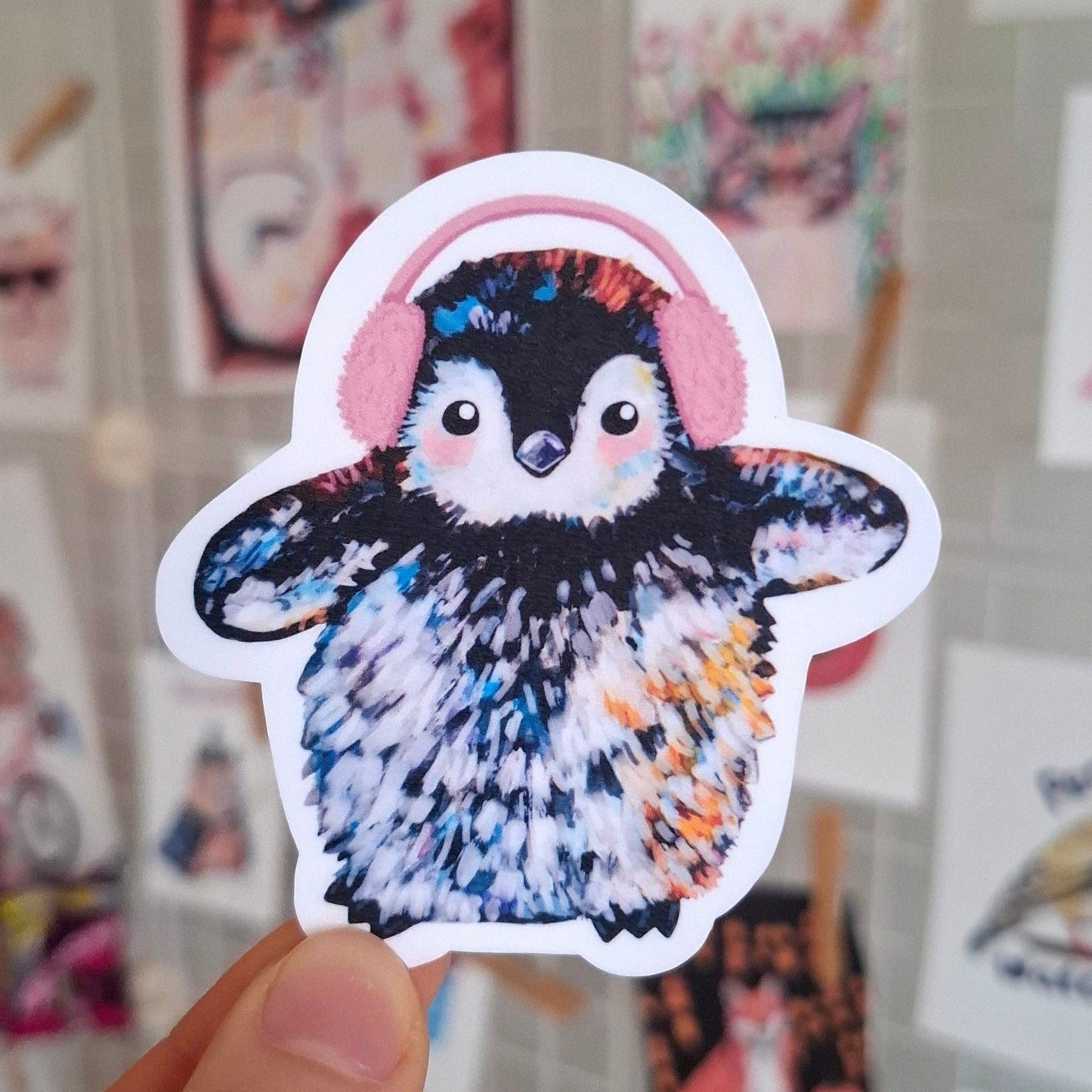 A cute penguin wearing pink ear muffs sticker.