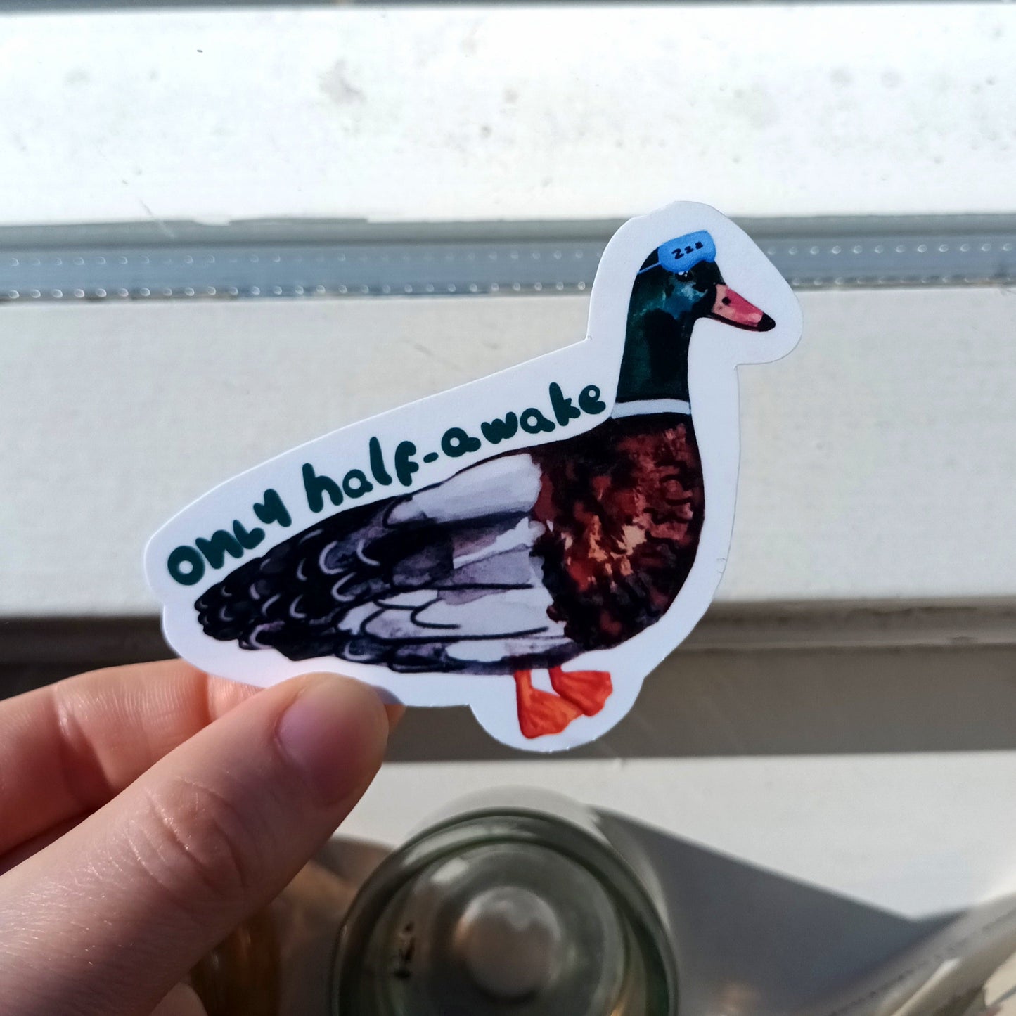 Sticker of a duck with 'only half awake' text .
