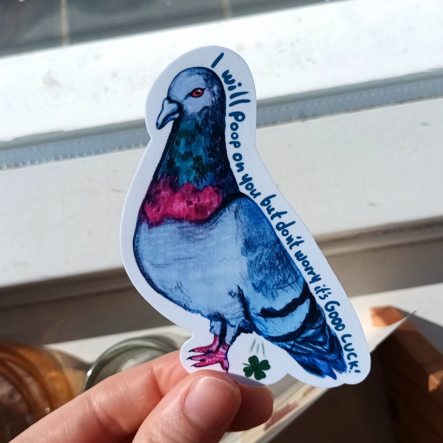 Sticker of a pigeon with text held by a hand .