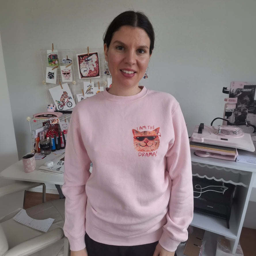Baby pink eco-friendly sweater with βI Am the Drama Catβ design, made from organic cotton and recycled polyester.