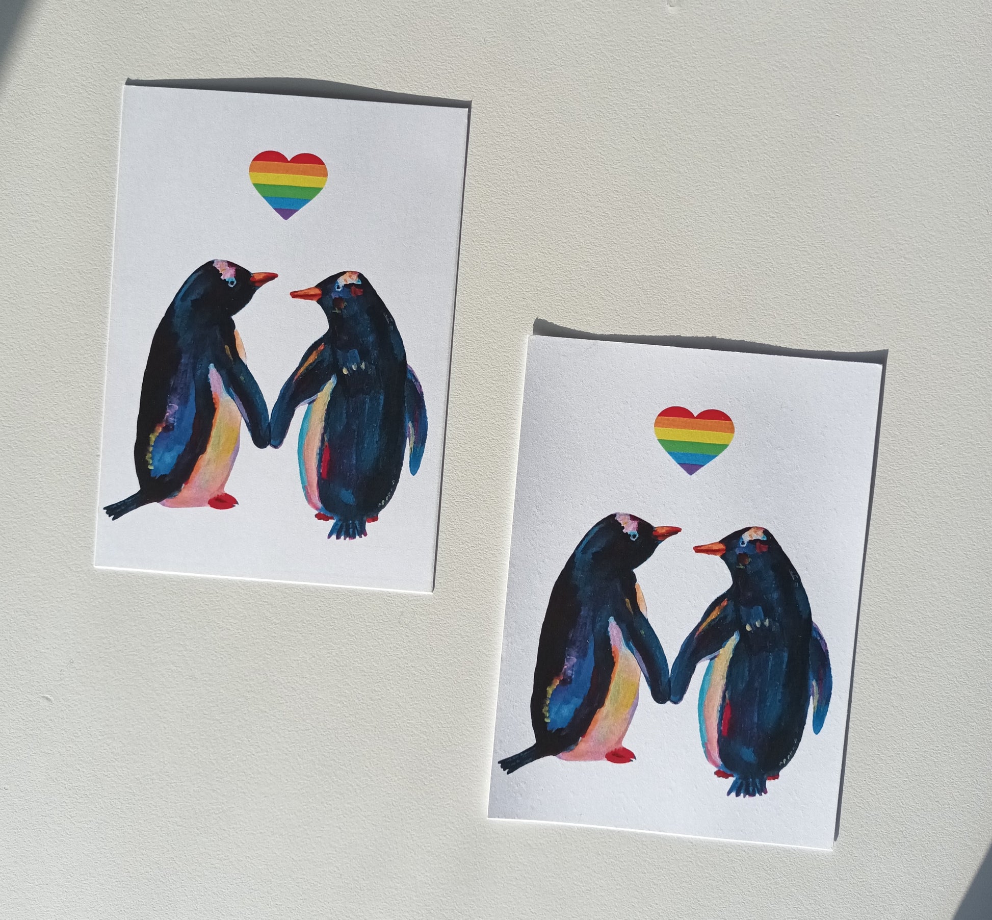 Handmade postcard featuring two adorable penguins in love, celebrating LGBTQ+ pride, high-quality illustration art card on table