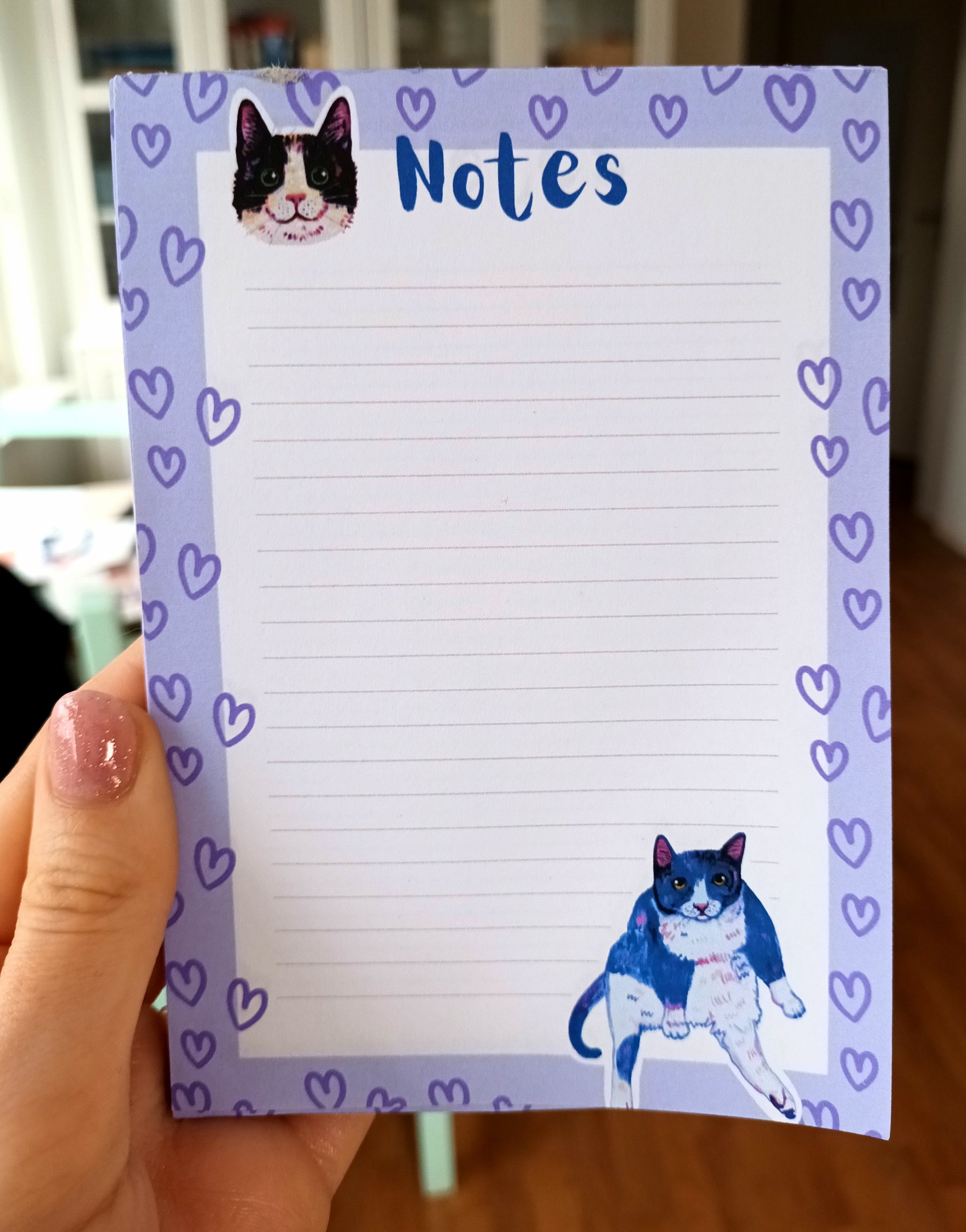 Sassy and cute cat-themed notepad in blue-purple tones, available in 30 or 50 pages, eco-friendly paper with sturdy cardboard backing held by hand