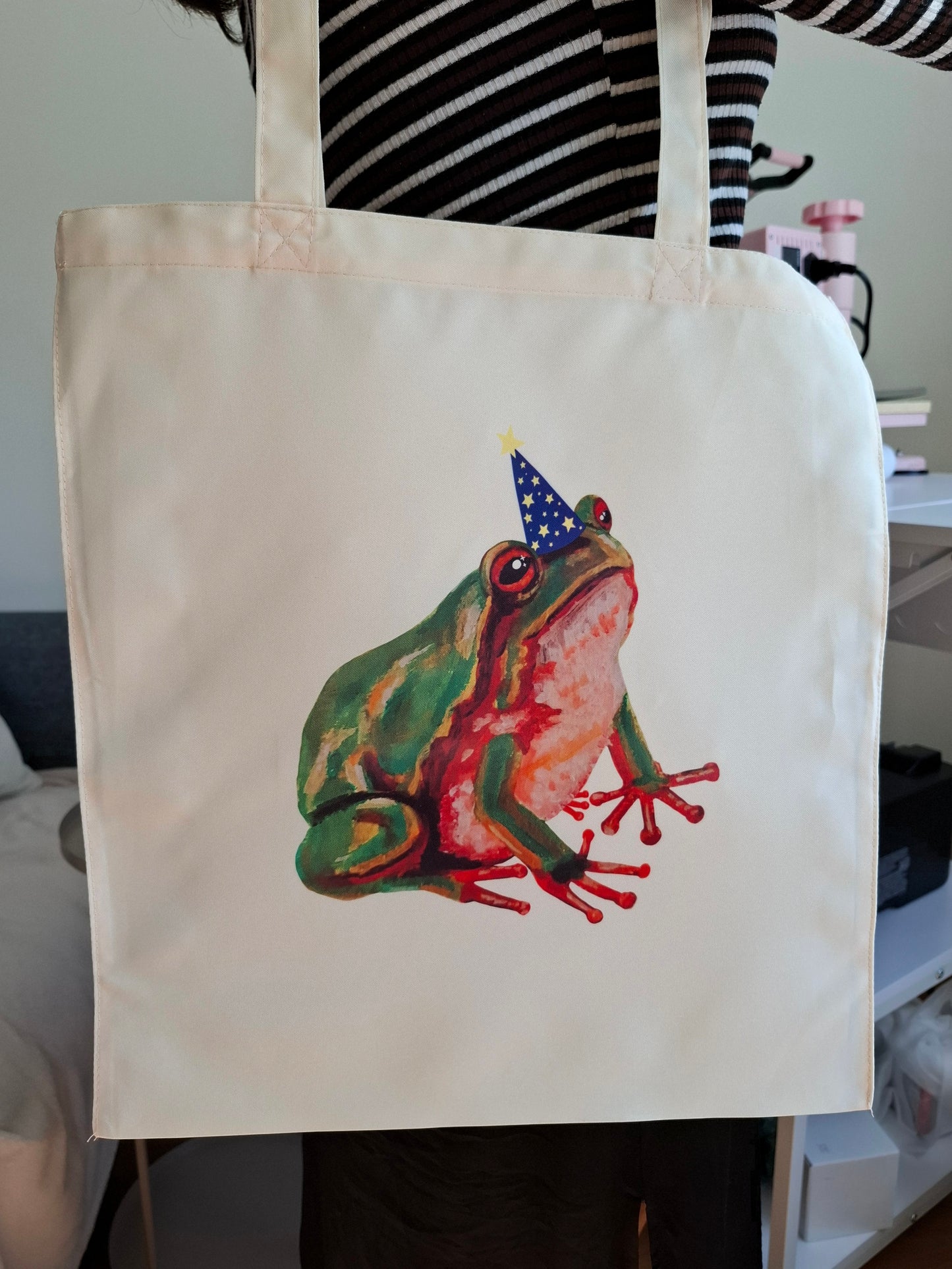 Handmade tote bag with a hand-painted design of a green frog wearing a magician hat, printed on both sides closeup