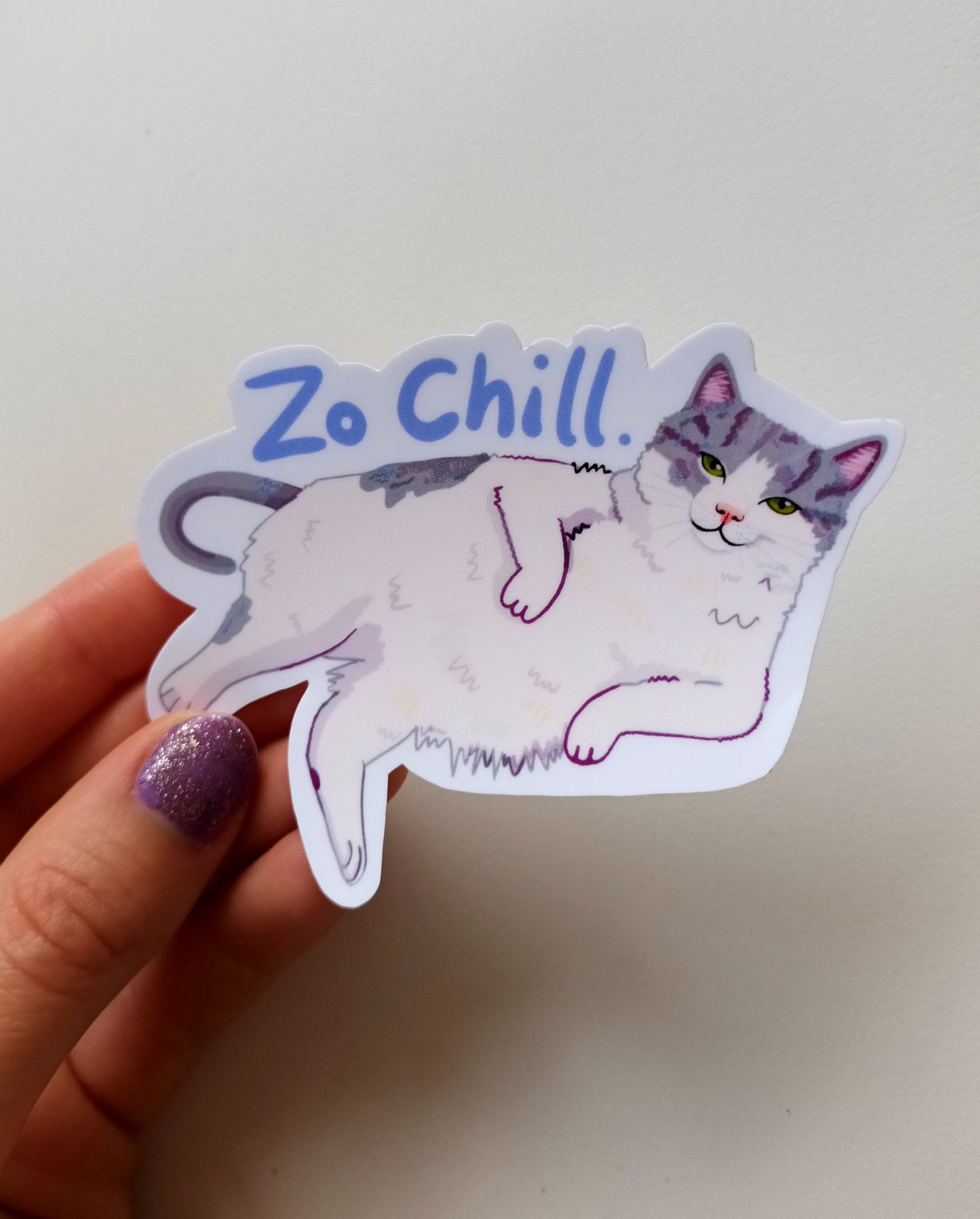 Sassy tuxedo cat vinyl sticker titled "Zo Chill" featuring a relaxed cat laying down, size 9 x 6.77 cm, handmade and waterproof held by hand