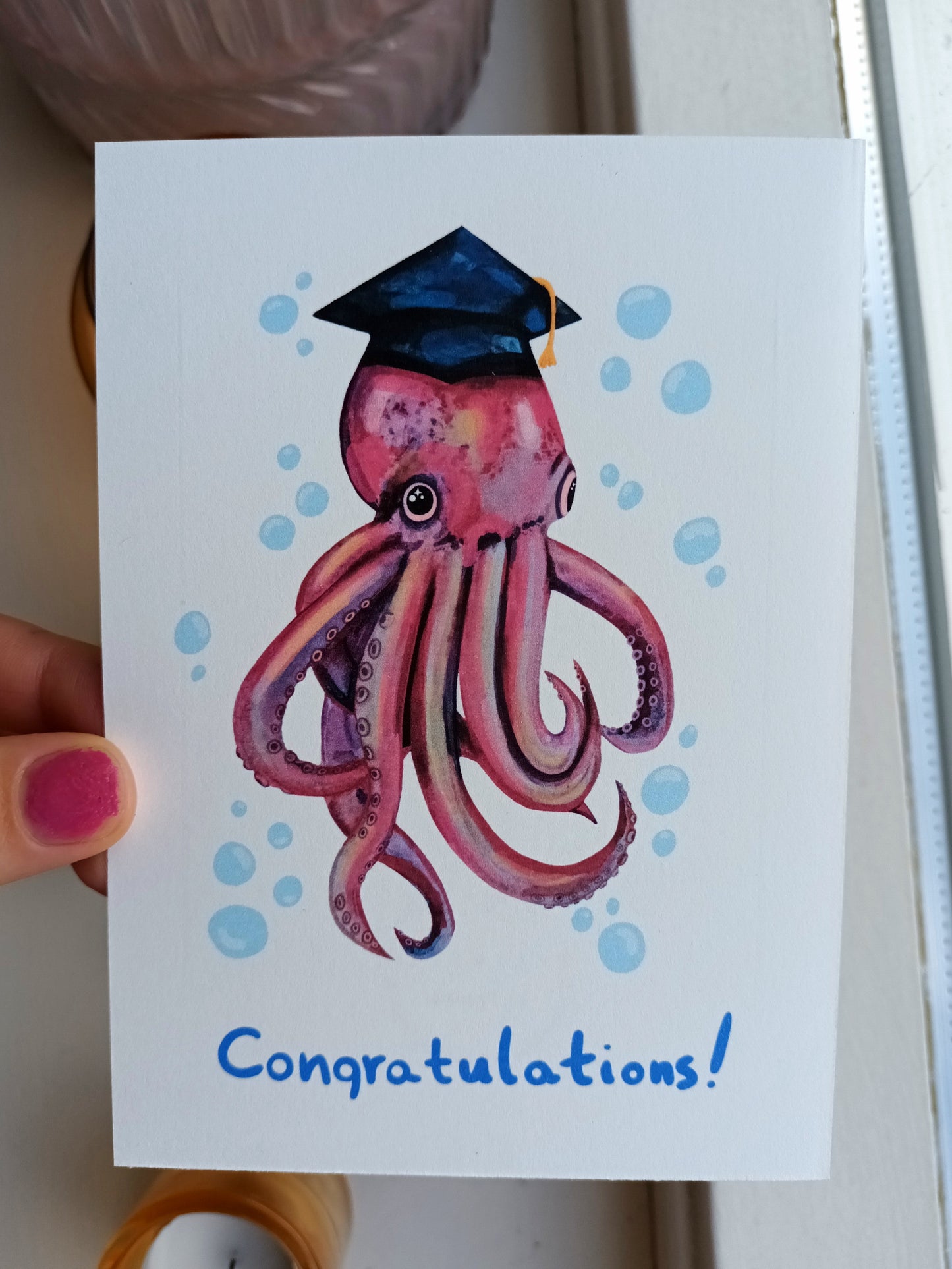 Graduation card featuring a cute octopus wearing a graduation cap with the word "Congratulations"