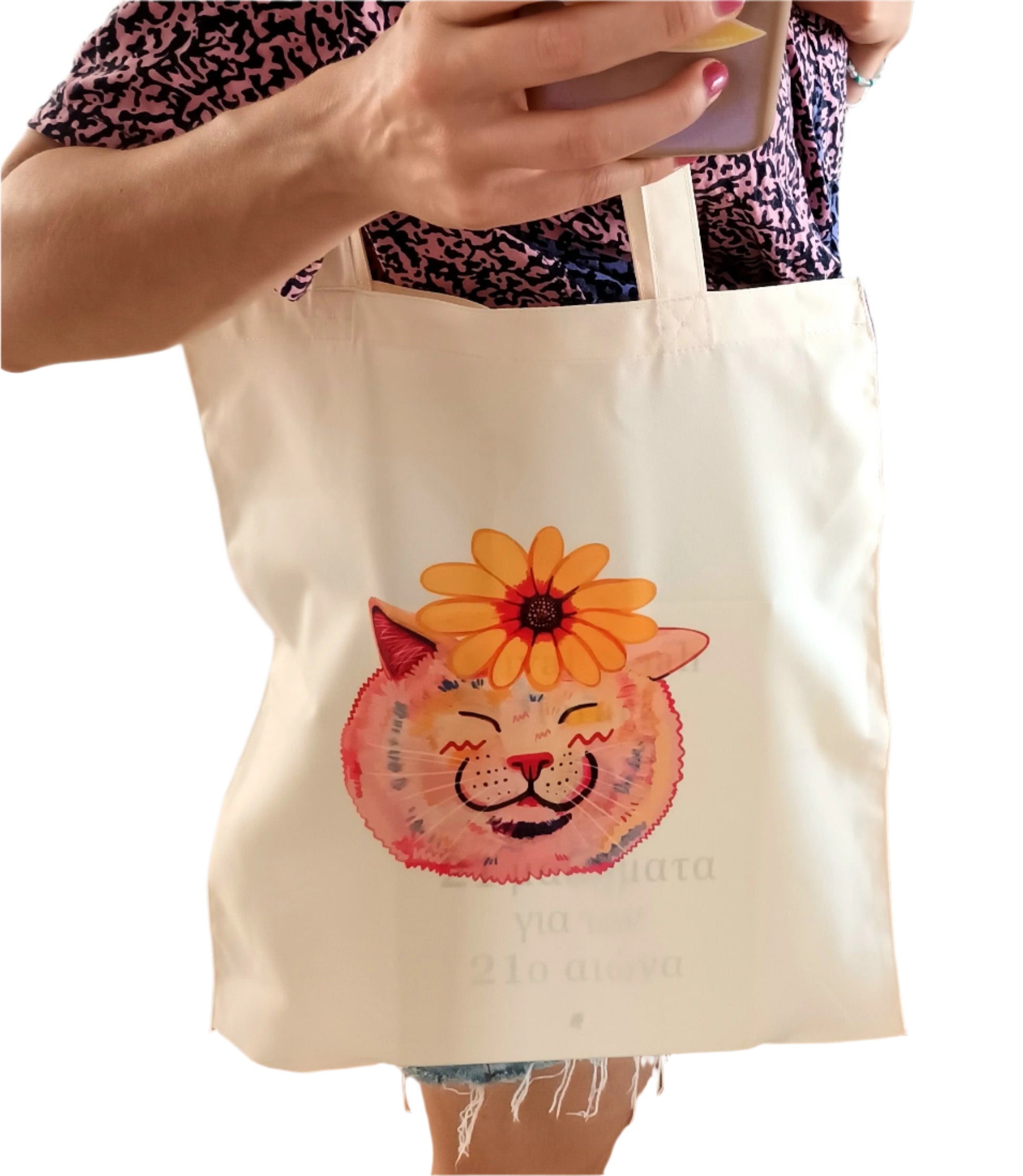 Person holding a tote bag with a colorful cat and sunflower its head.