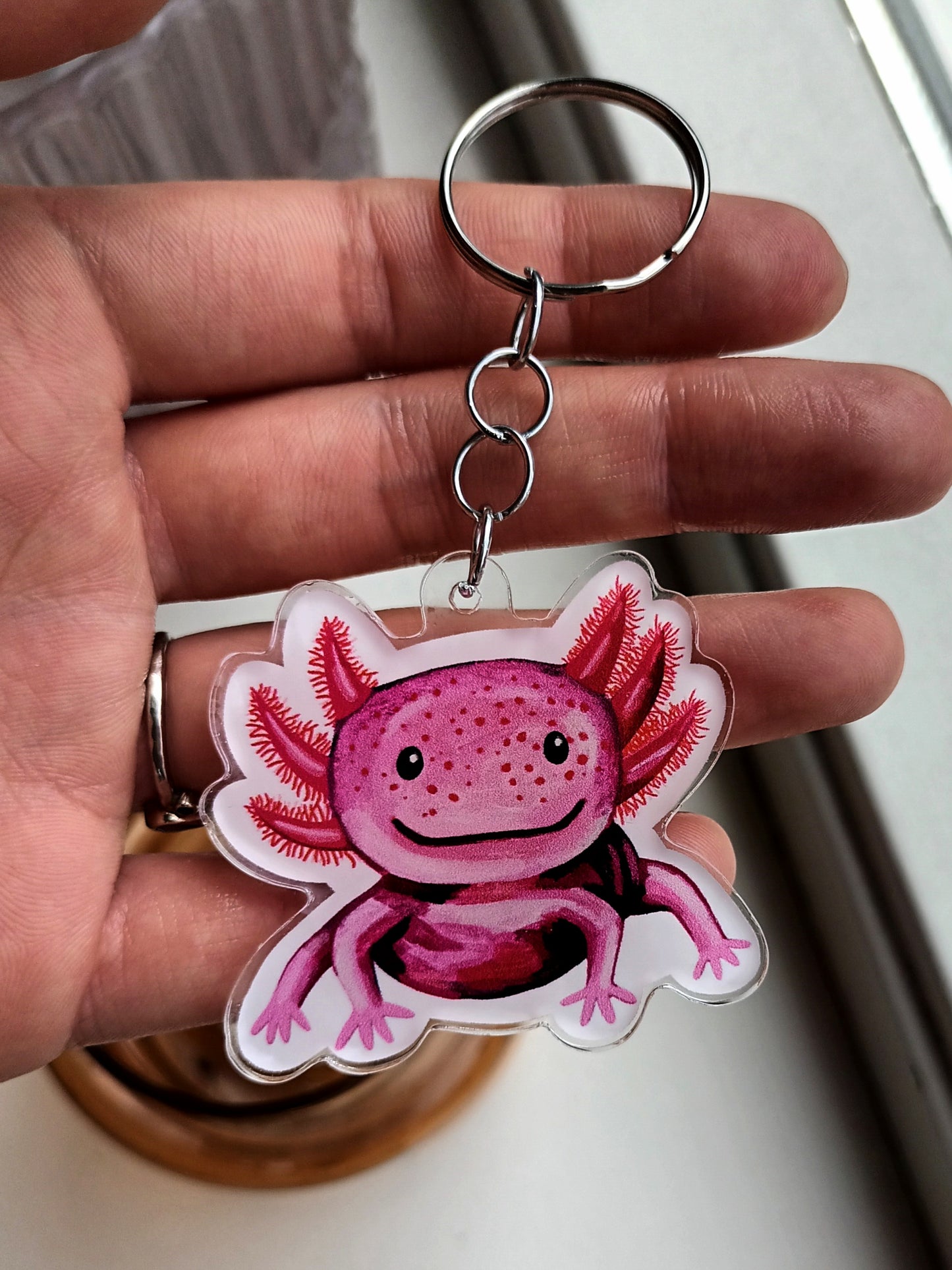 Acrylic keychain with a cute pink axolotl design, attached to a stainless steel key ring. Approx. 5 x 5 cm.