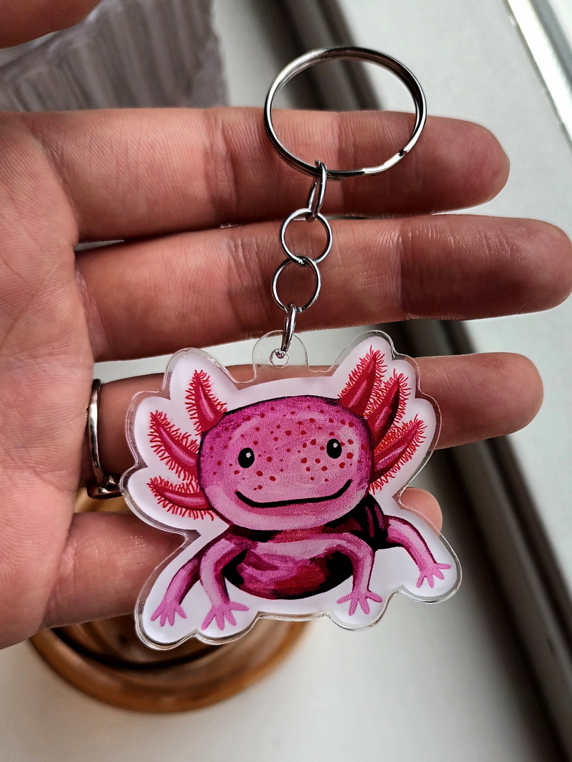 Acrylic keychain with a cute pink axolotl design, attached to a stainless steel key ring. Approx. 5 x 5 cm.