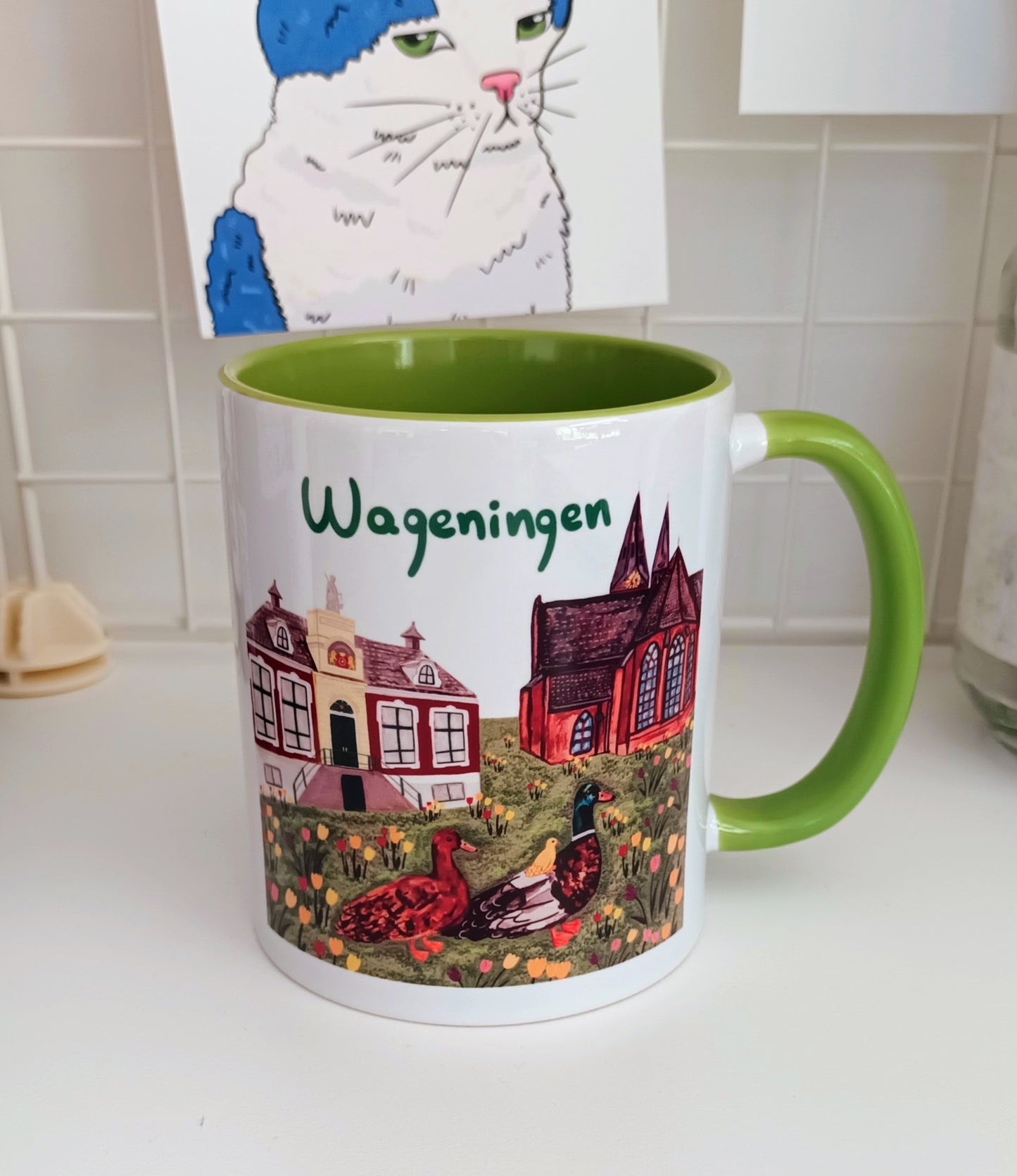 Hand-painted Wageningen mug with green handle and interior, featuring the municipality, church, blooming tulips, and a cute duck family.