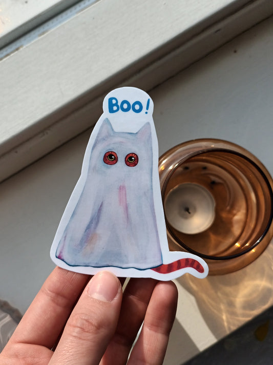 Hand holding a cat ghost sticker with 'Boo!' text 