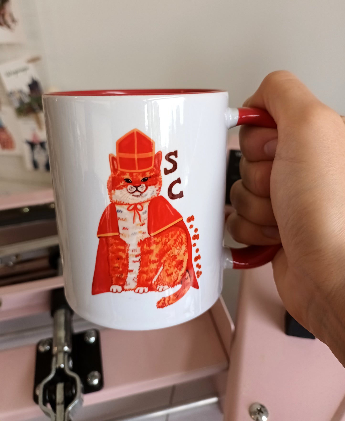 Handmade ceramic Sintercat mug with festive cat illustration, red handle, and red interior