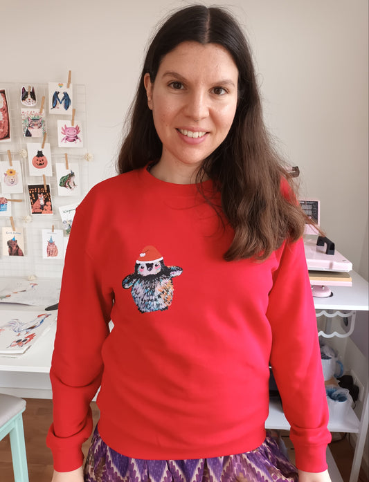 Red Christmas sweater made from organic cotton and recycled polyester, with cute penguin wearing Santa hat, printed by the artist.
