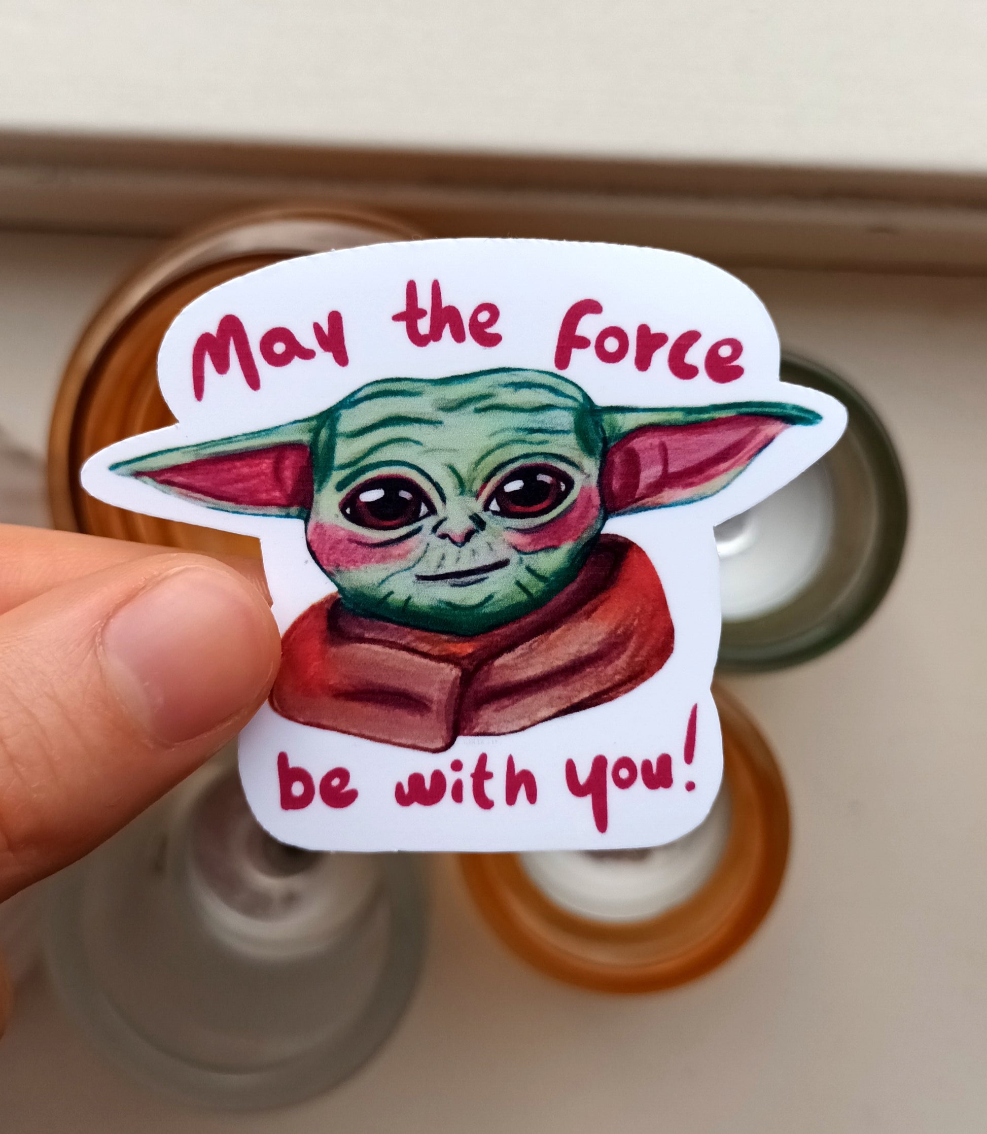 Cute Yoda fanart sticker with “May the force be with you” text, original illustration by the artist, 7 x 5.62 cm