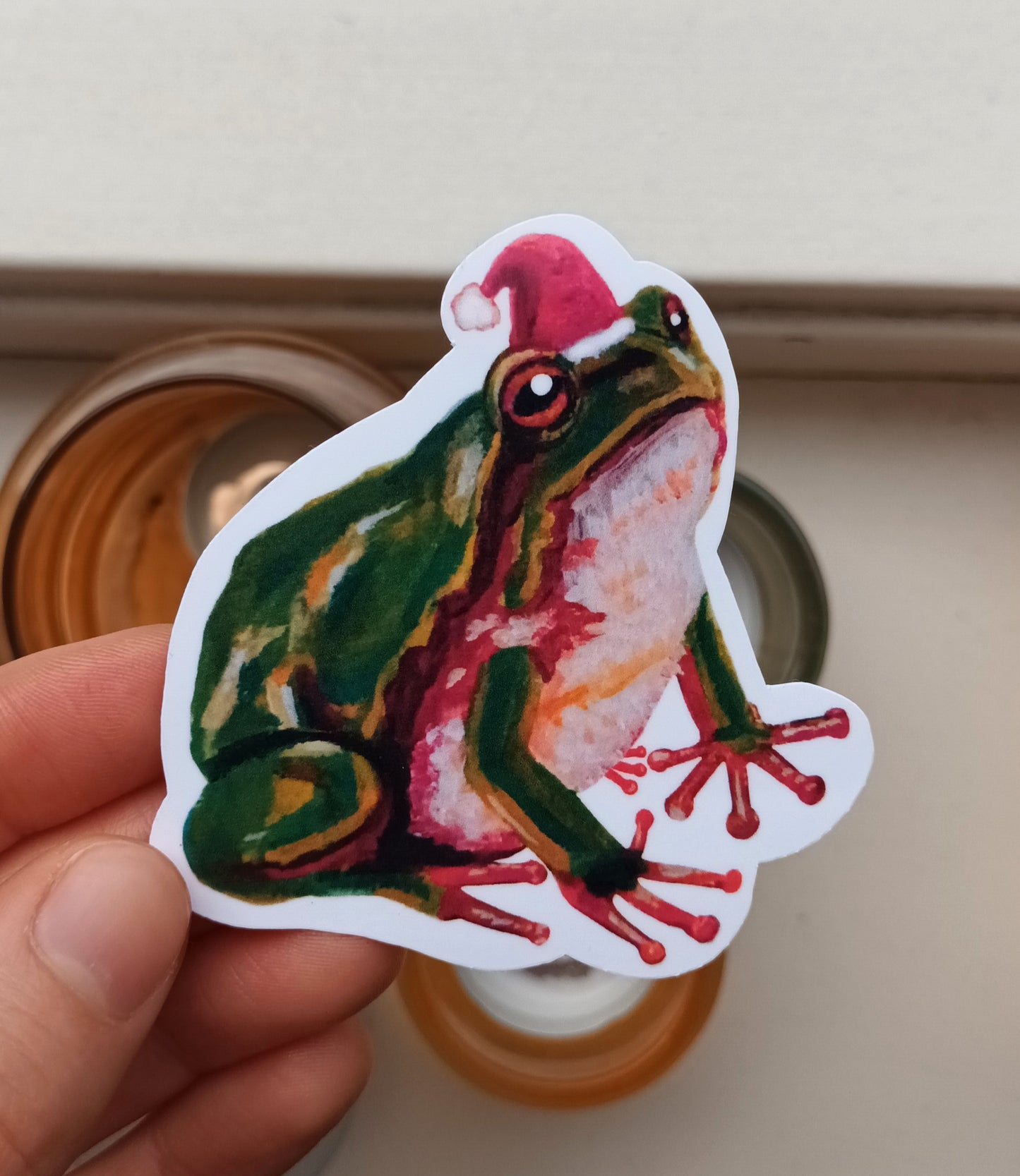 Cute frog wearing a Santa hat sticker, original festive illustration by the artist, 7 x 7.5 cm