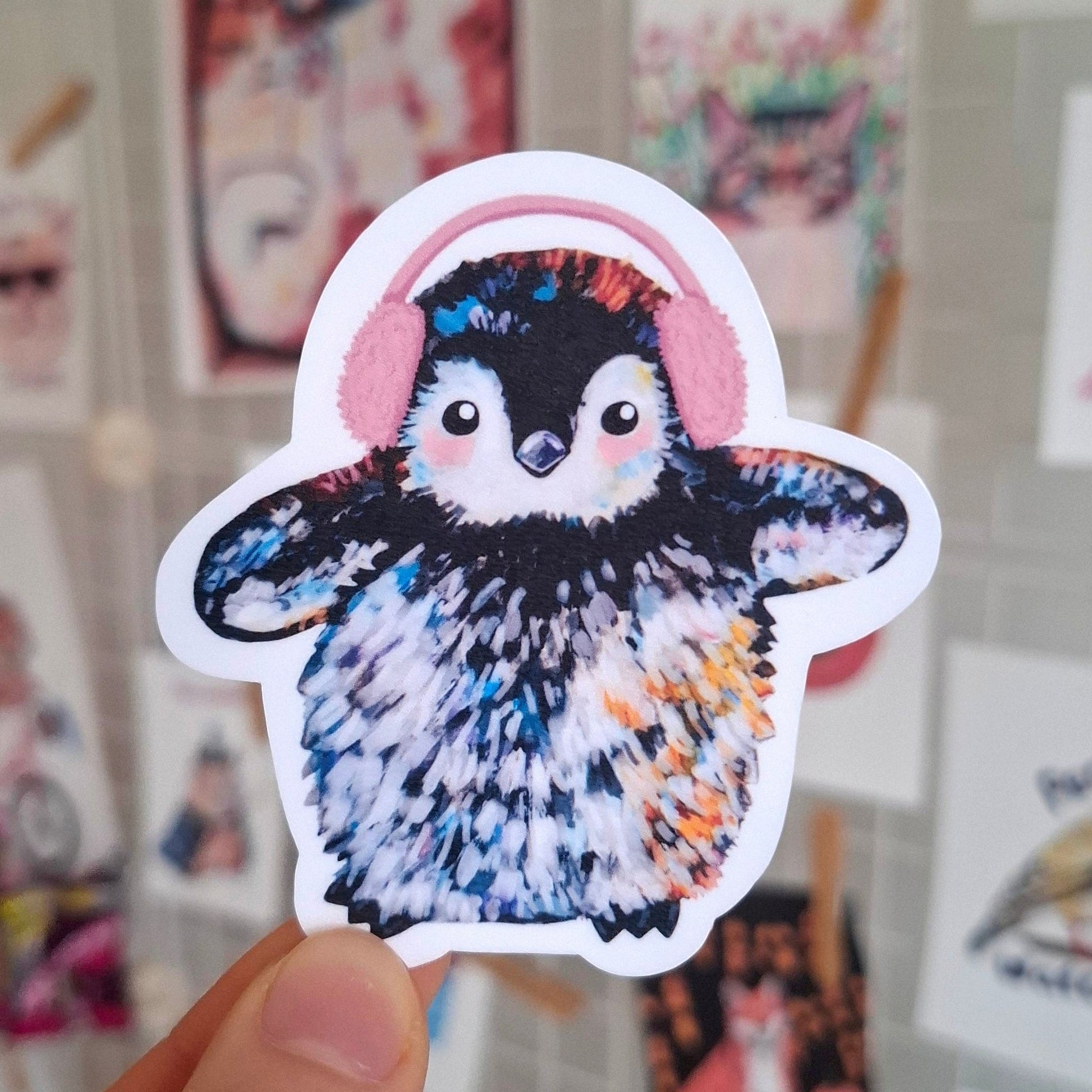 A cute penguin wearing pink ear muffs sticker.