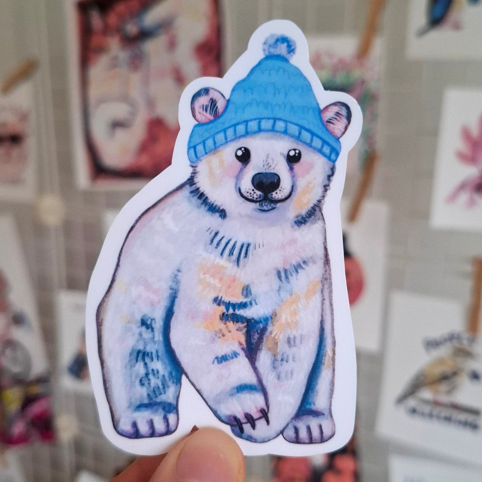 Sticker of a polar bear wearing a blue hat, cute winter sticker.