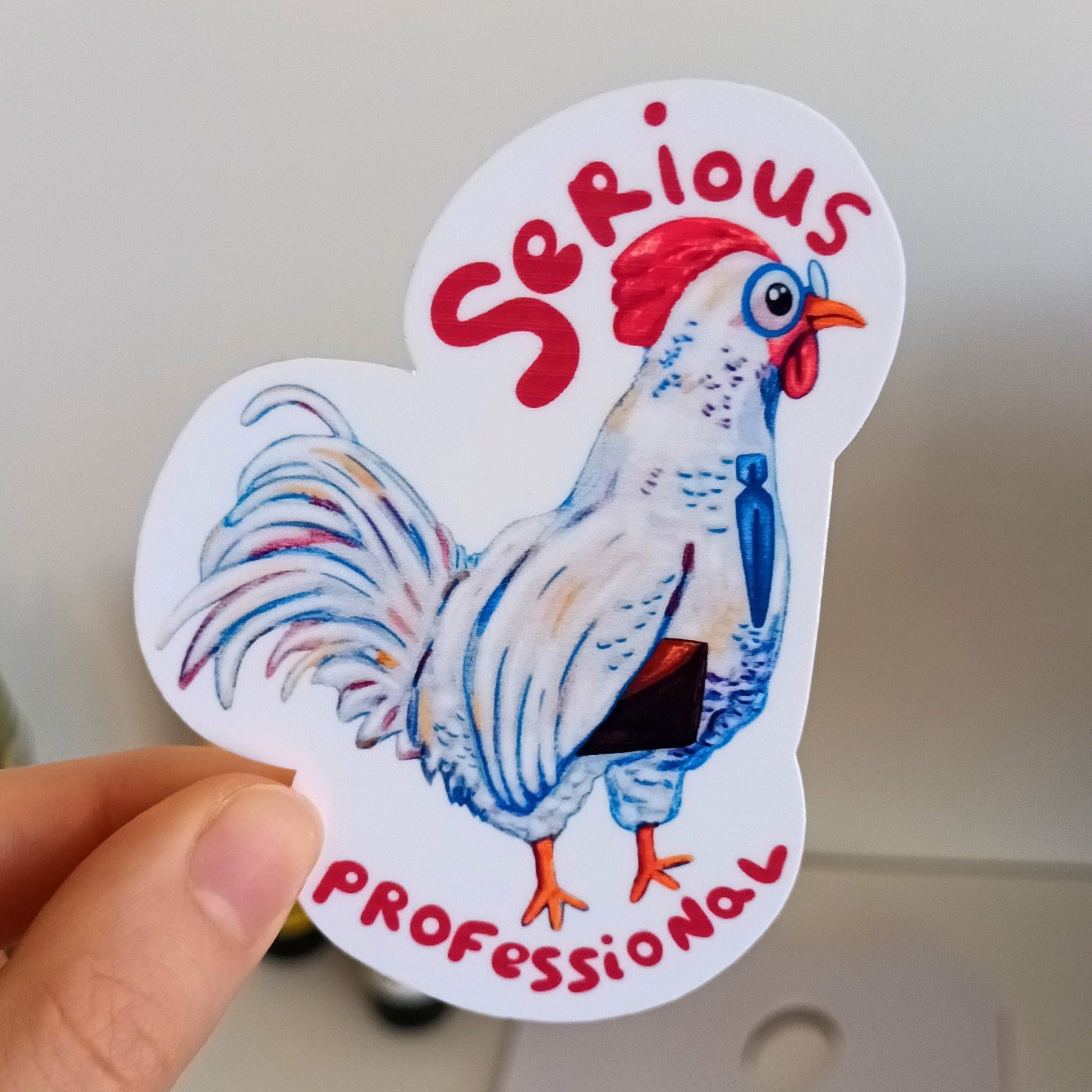 Hand holding a sticker with a rooster illustration and text 'Serious Professional'.