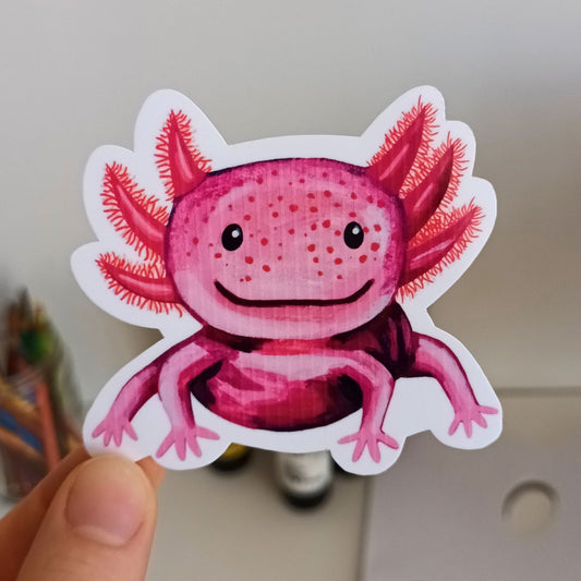 Hand holding a pink axolotl sticker .
