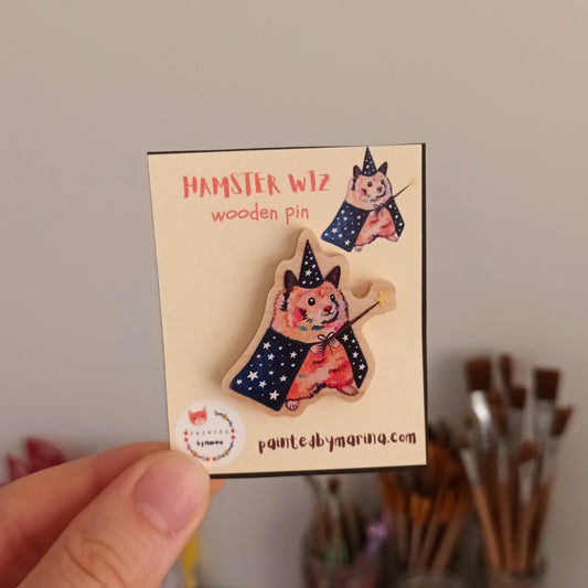 Hand holding a card with a wooden pin with a cute hamster wizard